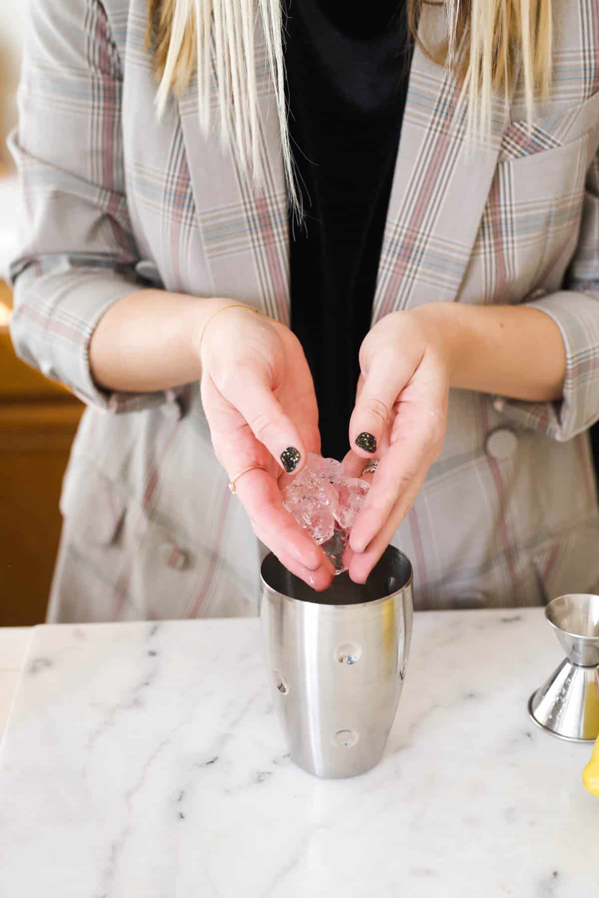 Woman adding ice to a cocktail shaker.