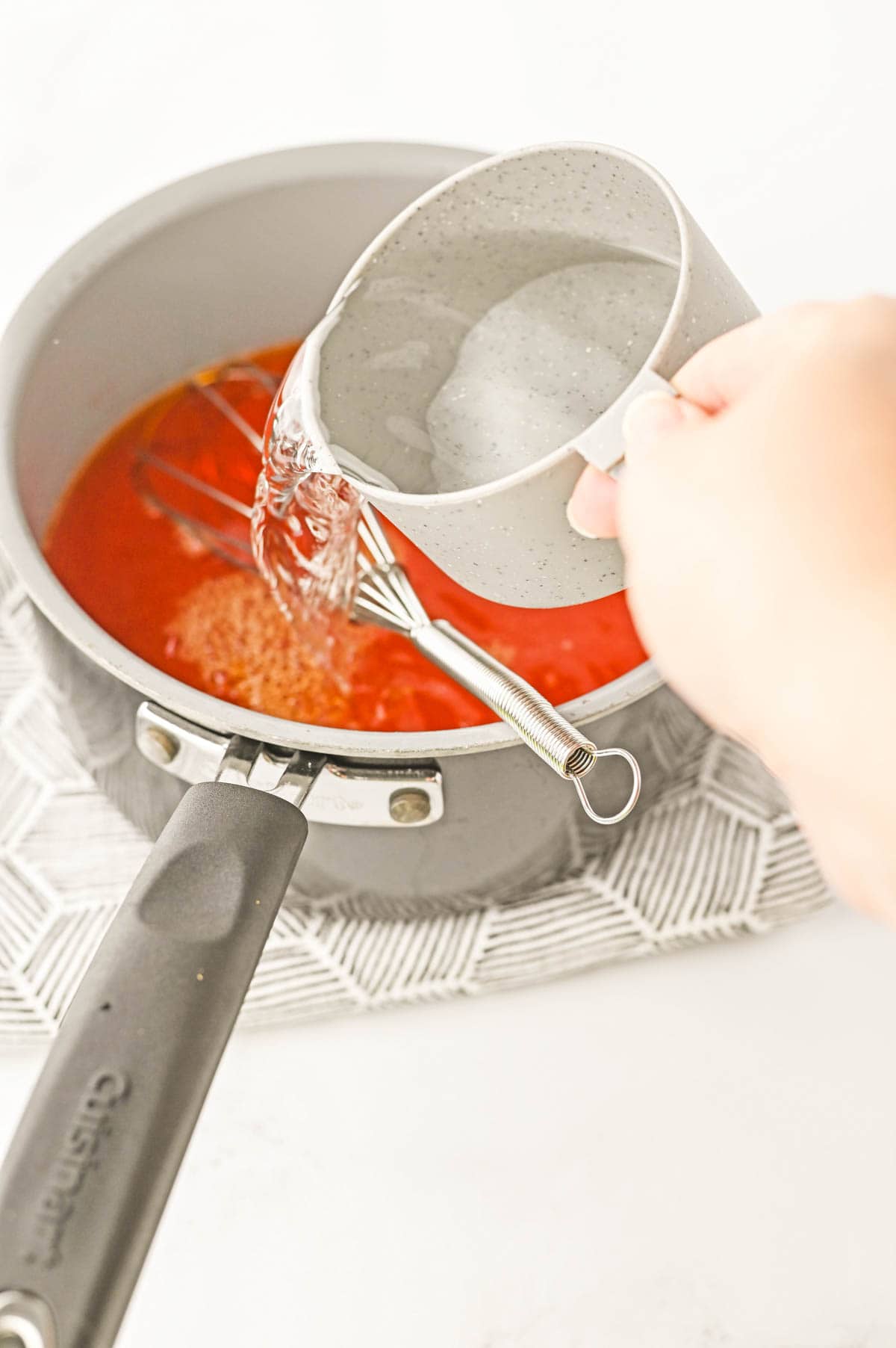 A cup of vodka being poured into orange Jello.