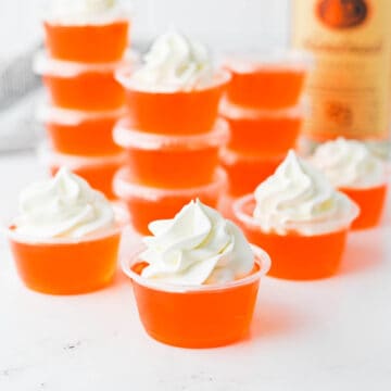 Orange Jello Shots topped with whipped cream.