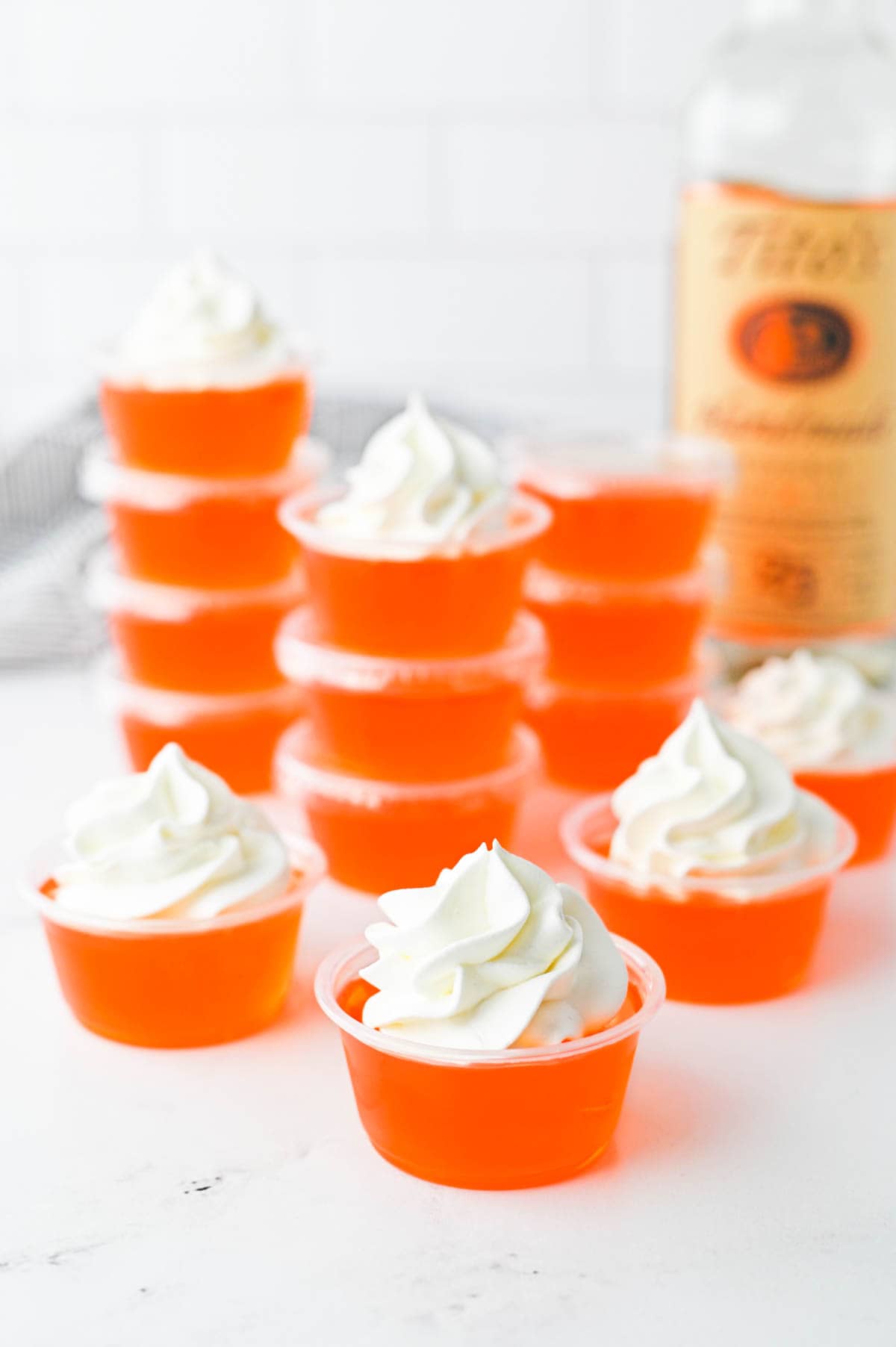 Orange Jello Shots topped with whipped cream.
