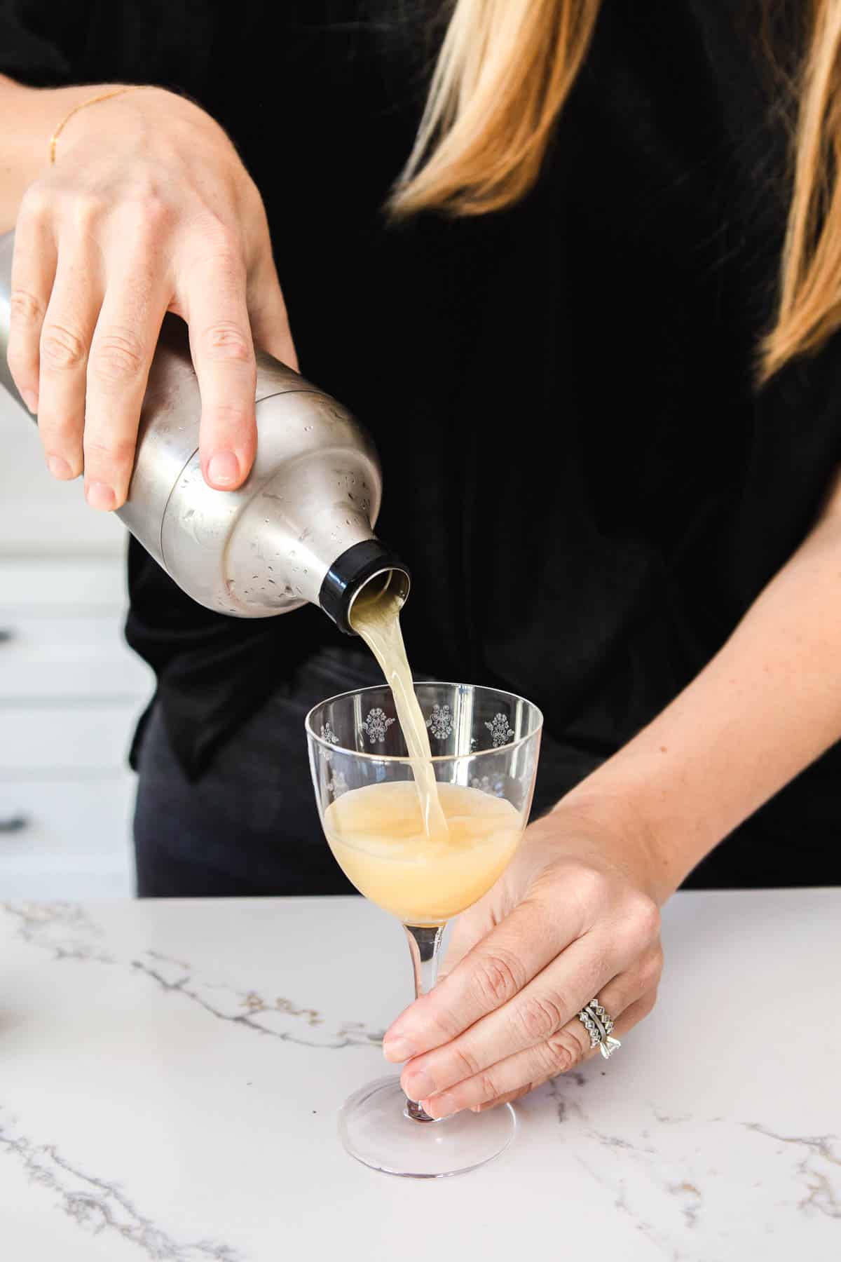 Woman pouring a sidecar into a cocktail glass.