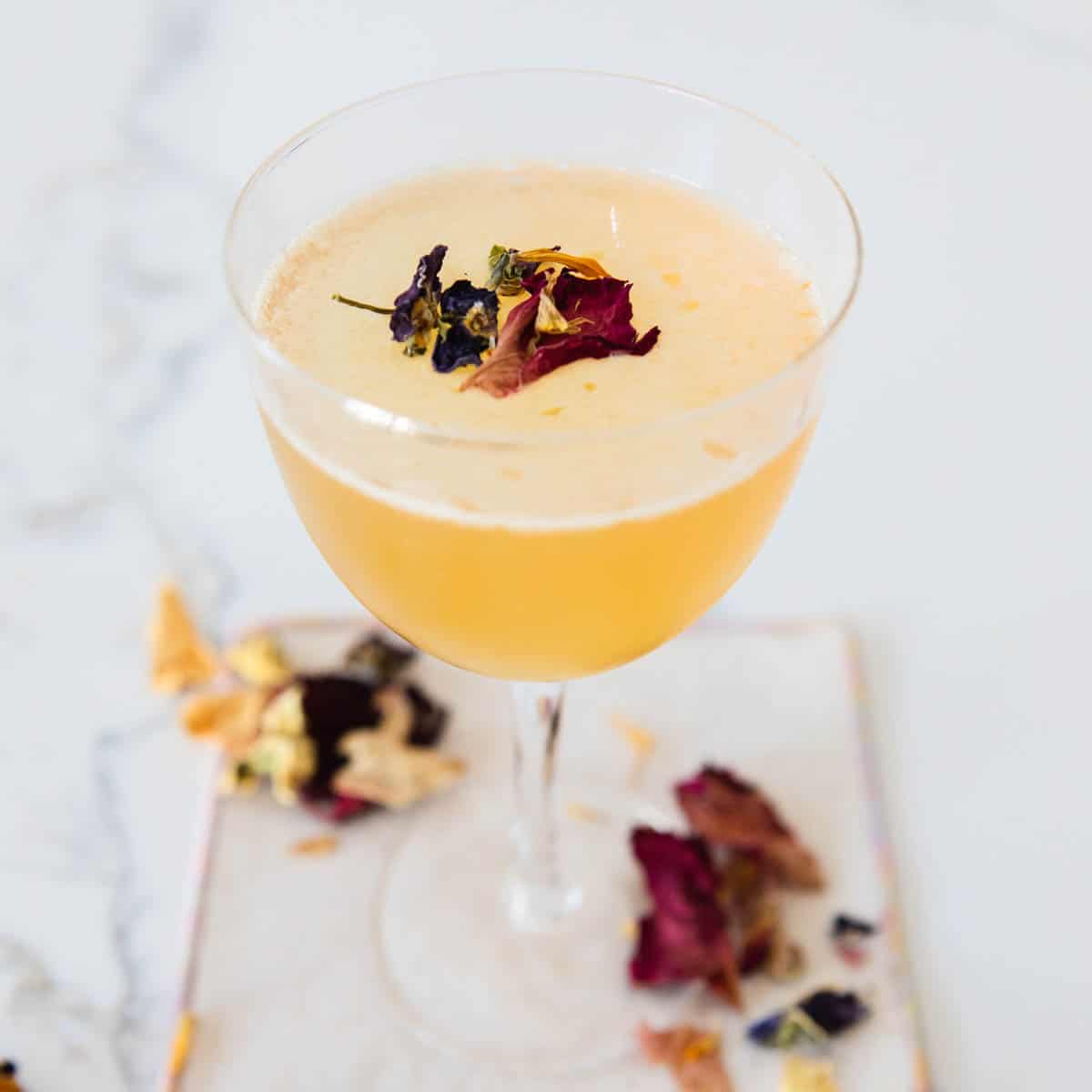 Close up of a sidecar garnished with edible dried flowers.