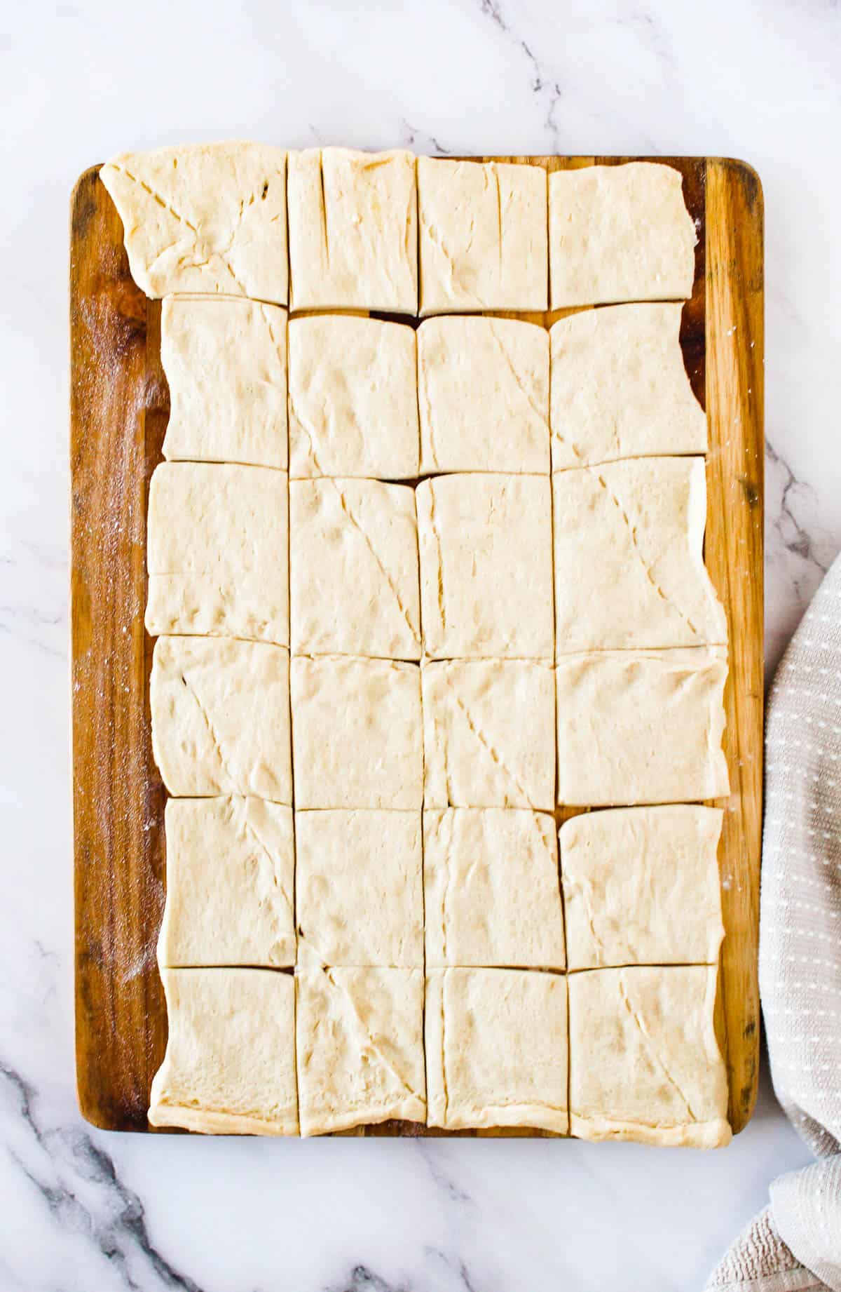 Crescent roll rolled out on a work surface and cut into small squares.