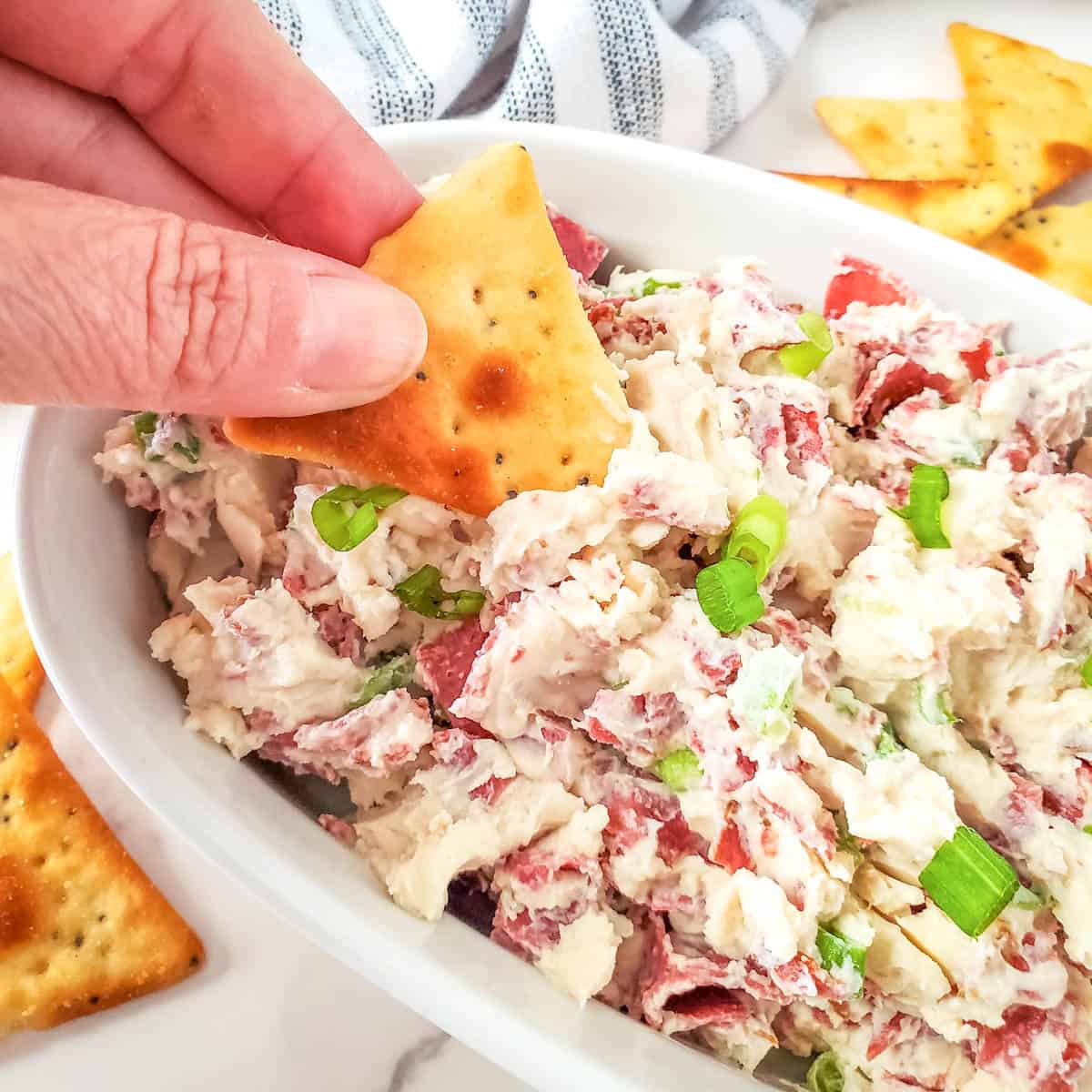 Dipping a piece of cracker in cream cheese dried beef dip.