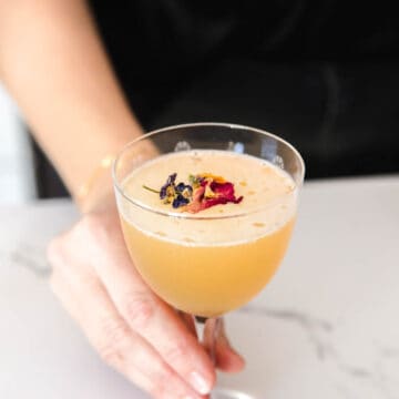 Woman serving a Bourbon Sidecar in a coupe glass.