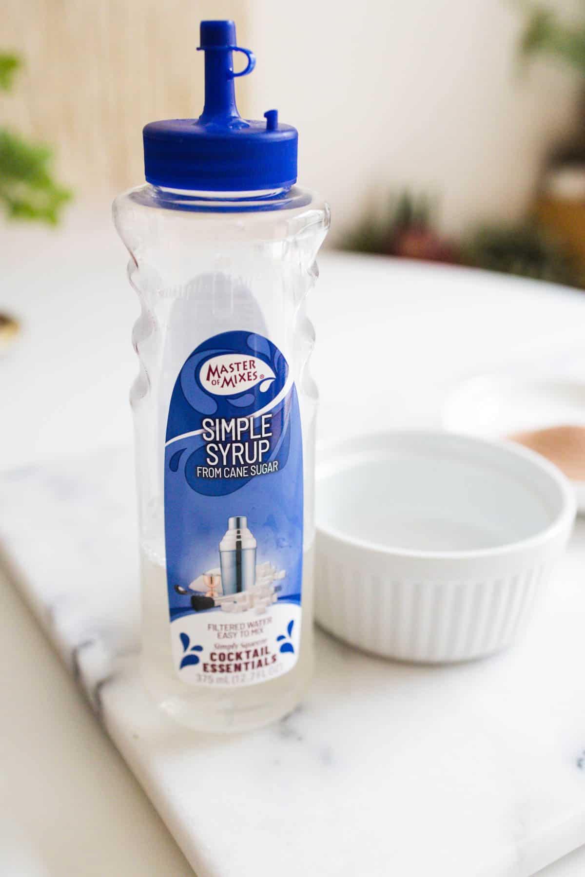 Bottle of simple syrup next to a white dish.