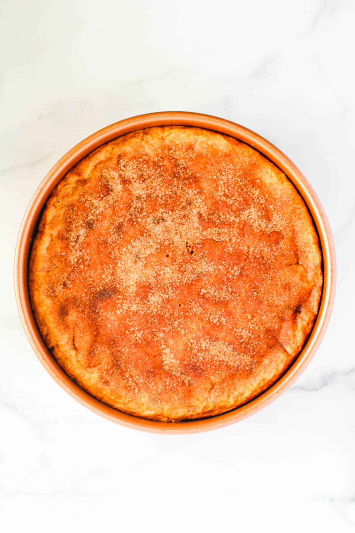 A cinnamon sugar dusted cookie dough pressed into a cake pan.