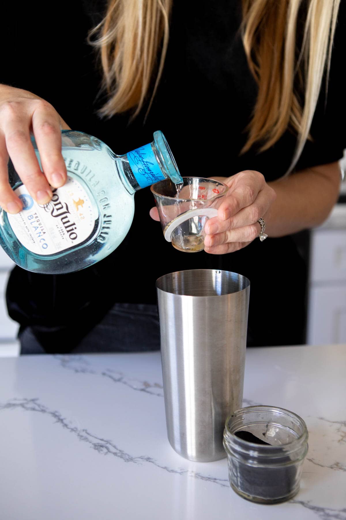 Woman pouring Don Julio tequila into a measuring cup and adding to a cocktail shaker.