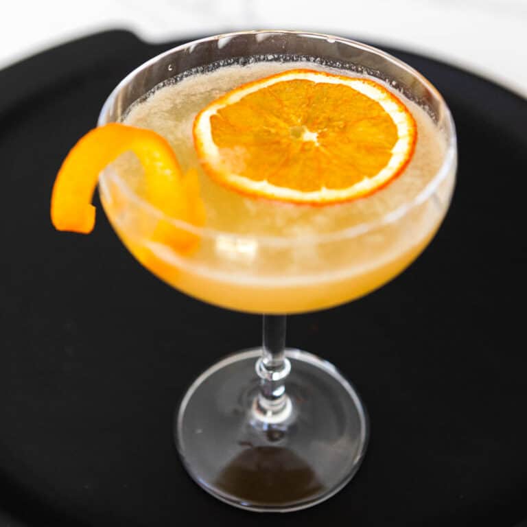 Close up of a whiskey cocktail garnished with fresh orange.