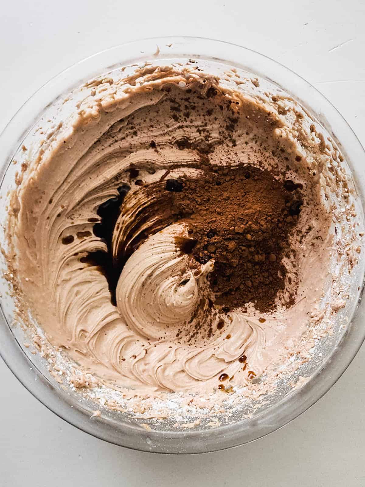 A mixing bowl with a buttercream frosting with hot cocoa mix powder in it for flavoring it.