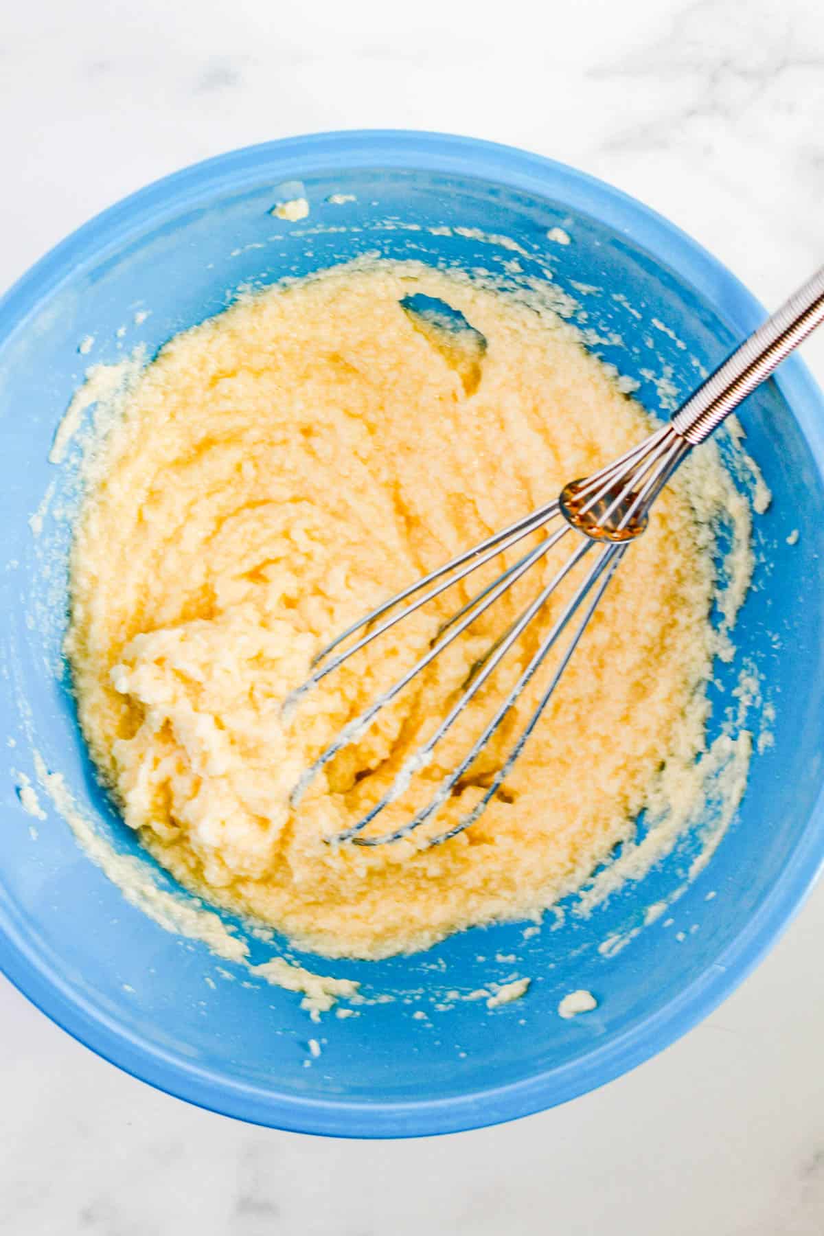 Cookie batter in a blue bowl with a whisk.