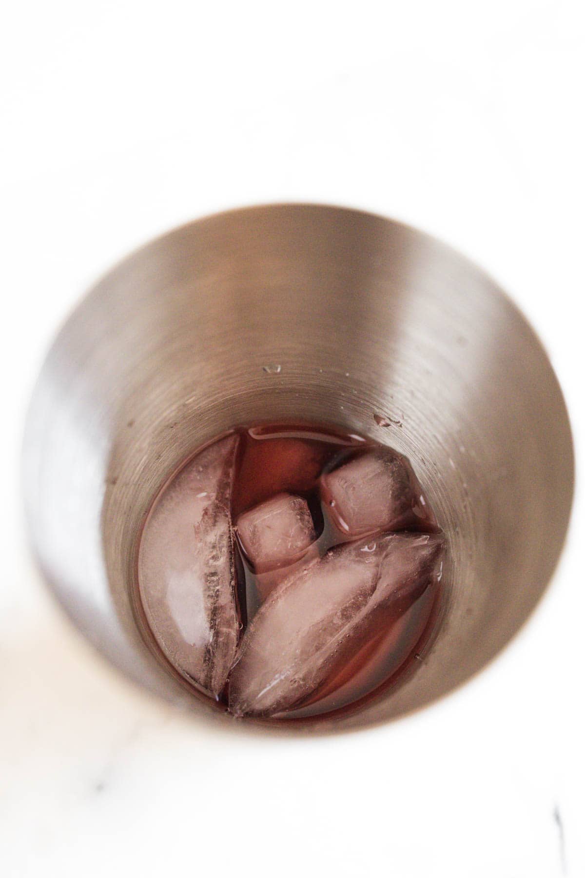 Cocktail shaker filled with cranberry juice and ice.