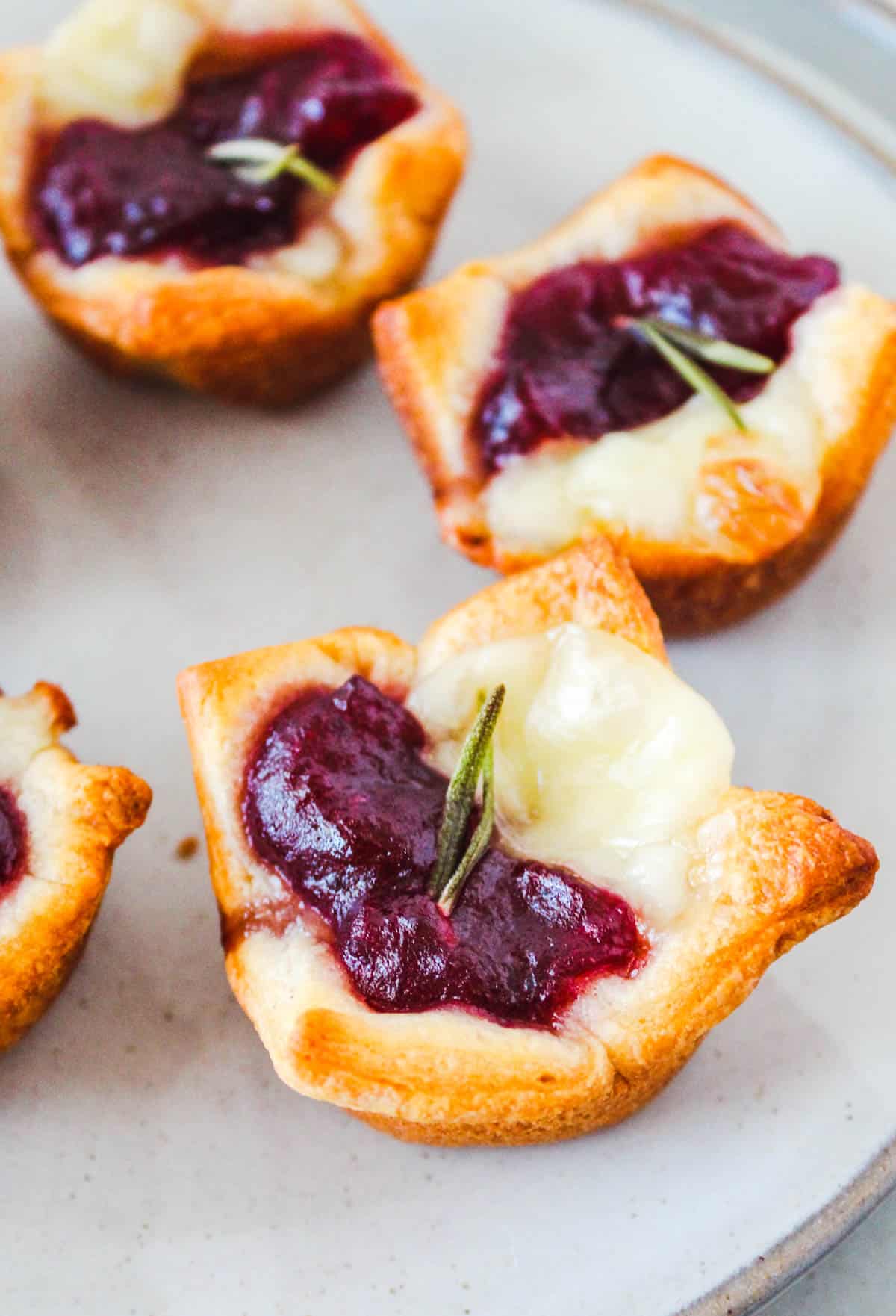 Close up image of brie and cranberry bites on a plate.