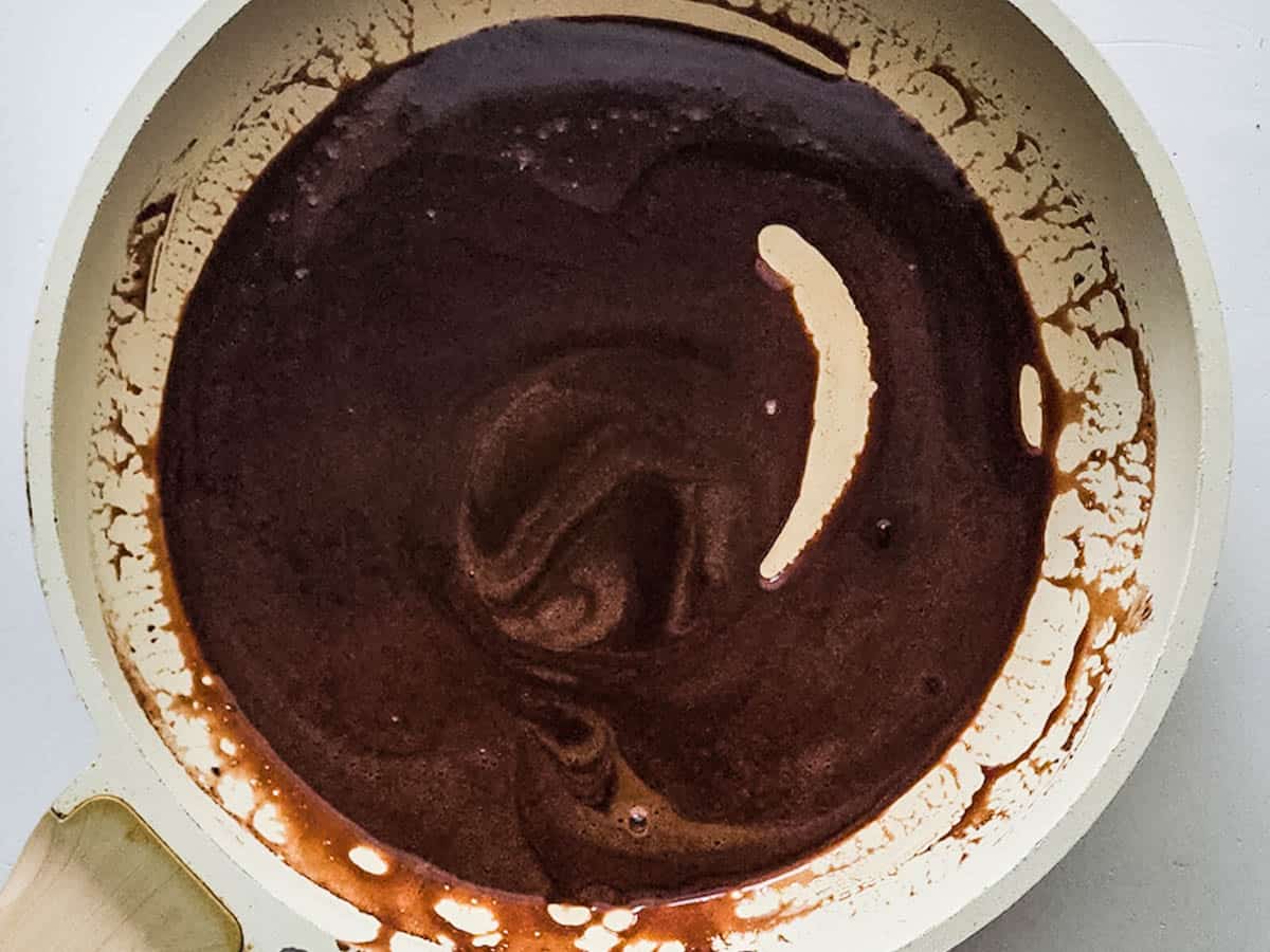 A skillet with melted chocolate in it for a hot chocolate buttercream frosting. 