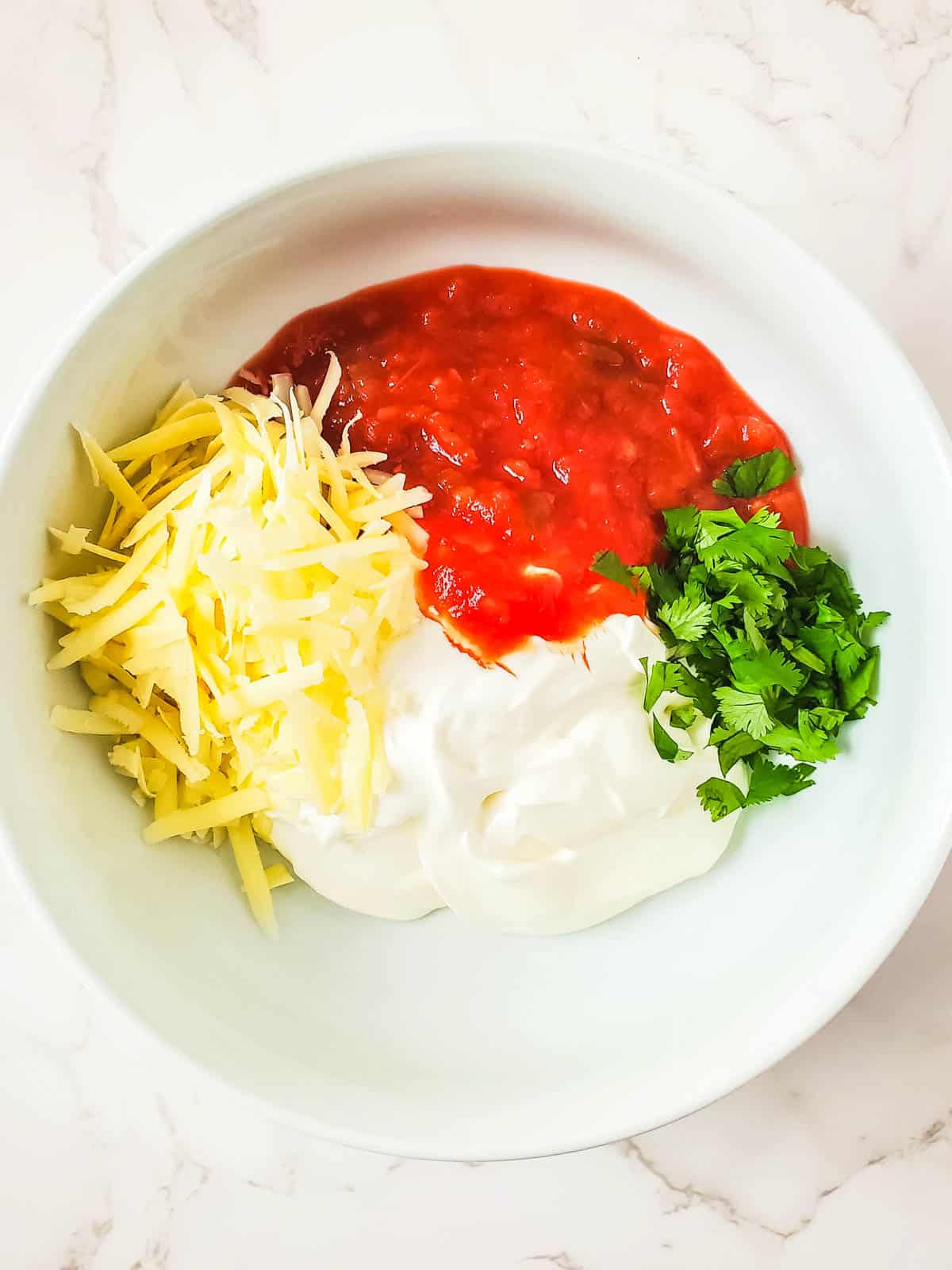 Ingredients for making a dip with salsa and sour cream on a mixing bowl.