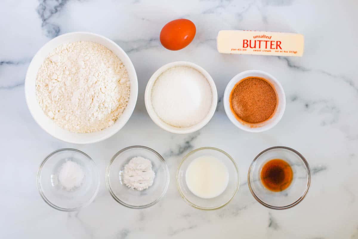 Ingredients to make a Snickerdoodle cookie cake separated into bowls on a counter.