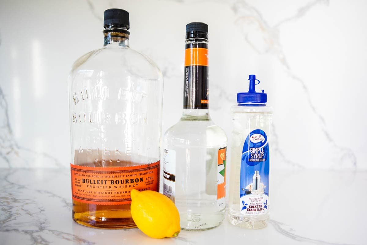 Bourbon Sidecar ingredients on a white marble countertop.