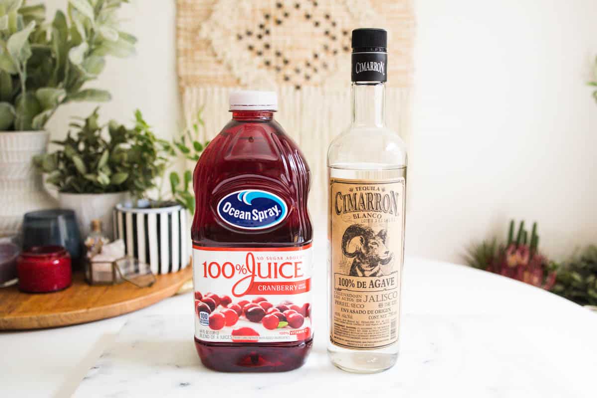 Bottles of cranberry juice and tequila on the countertop.