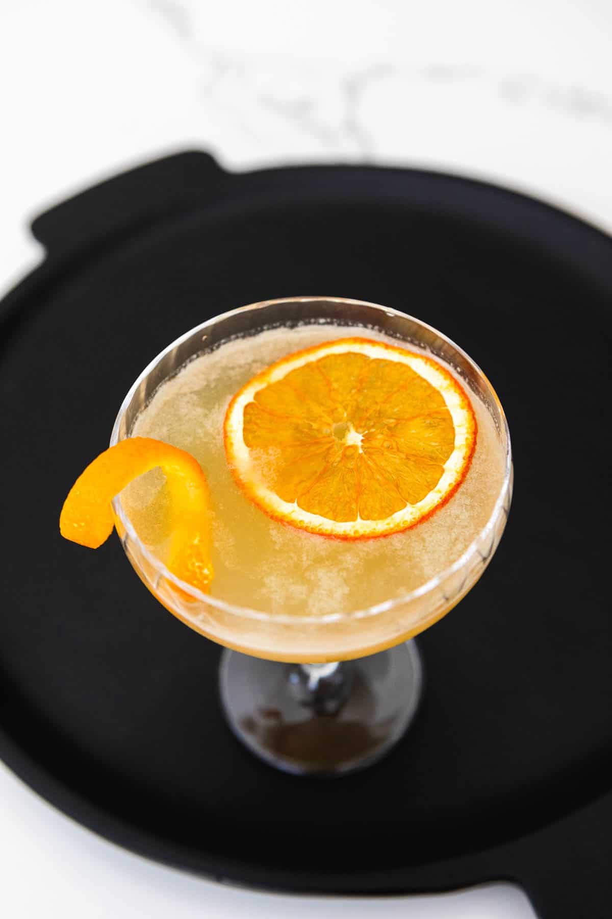 A whiskey sour garnished with an orange wheel and twist.