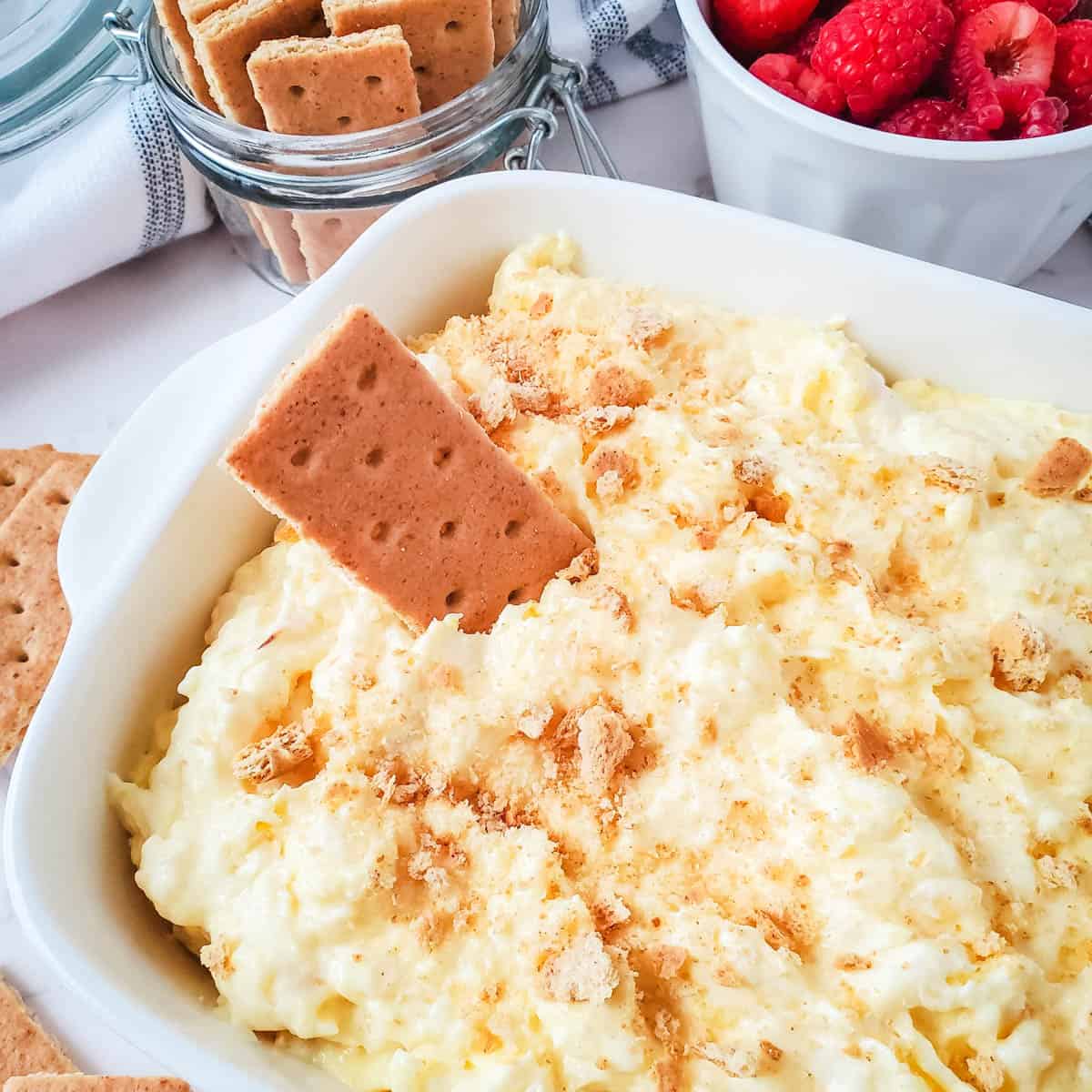 Pineapple dip with cream cheese on a dipping bowl with graham crackers and fresh fruit for dipping.