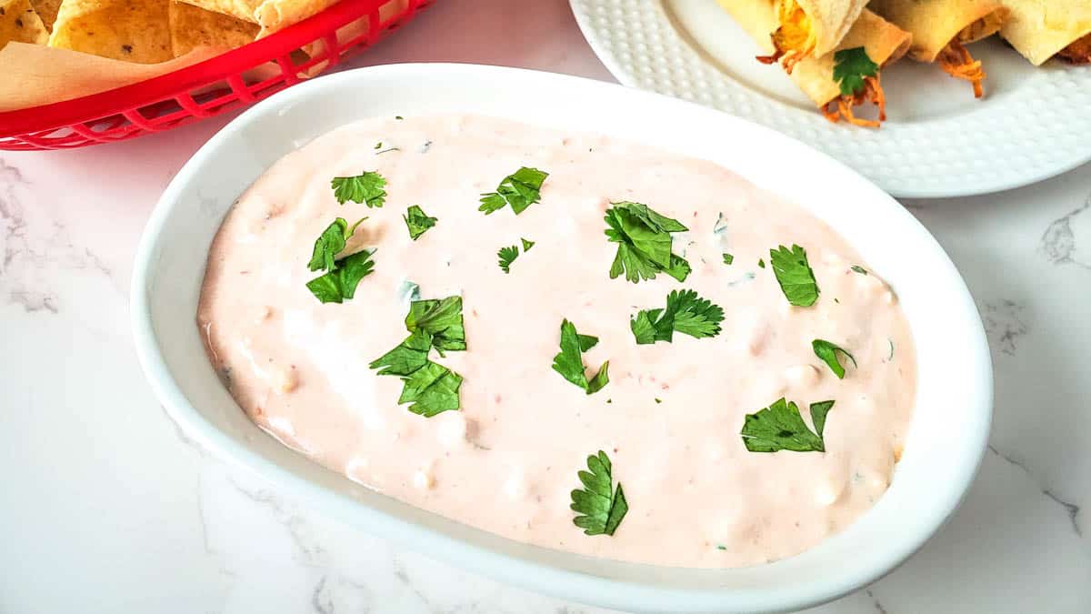 Salsa and sour cream dip topped with herbs on an oval serving plate.