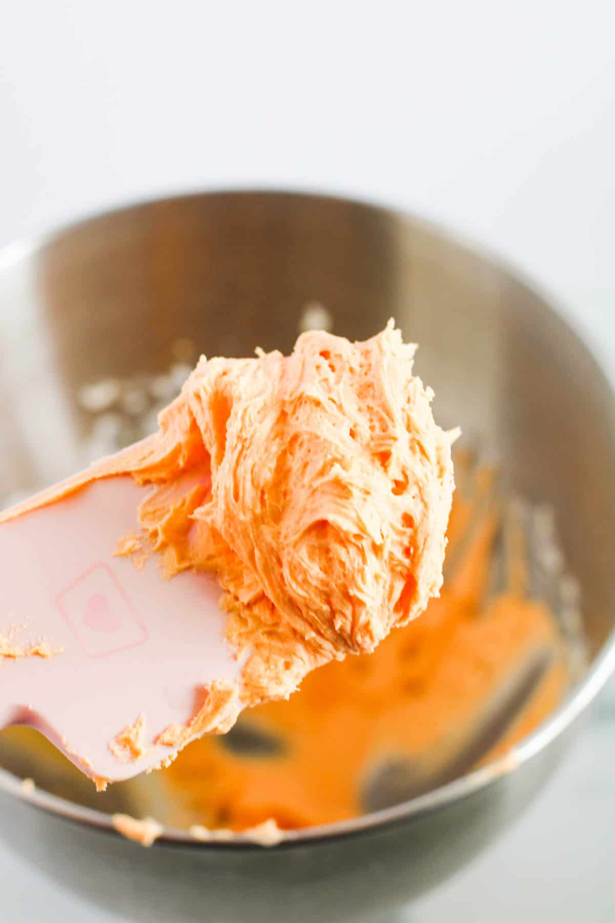 Orange frosting on a spatula.