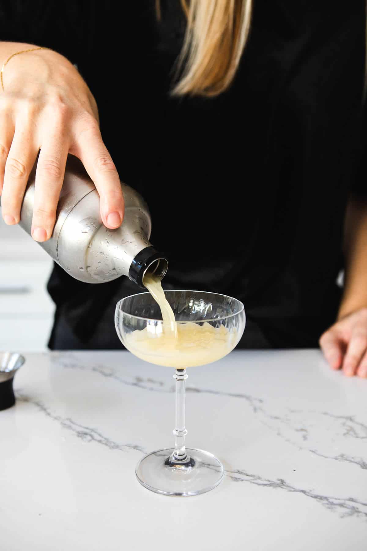Woman pouring a drink into a cocktail glass.