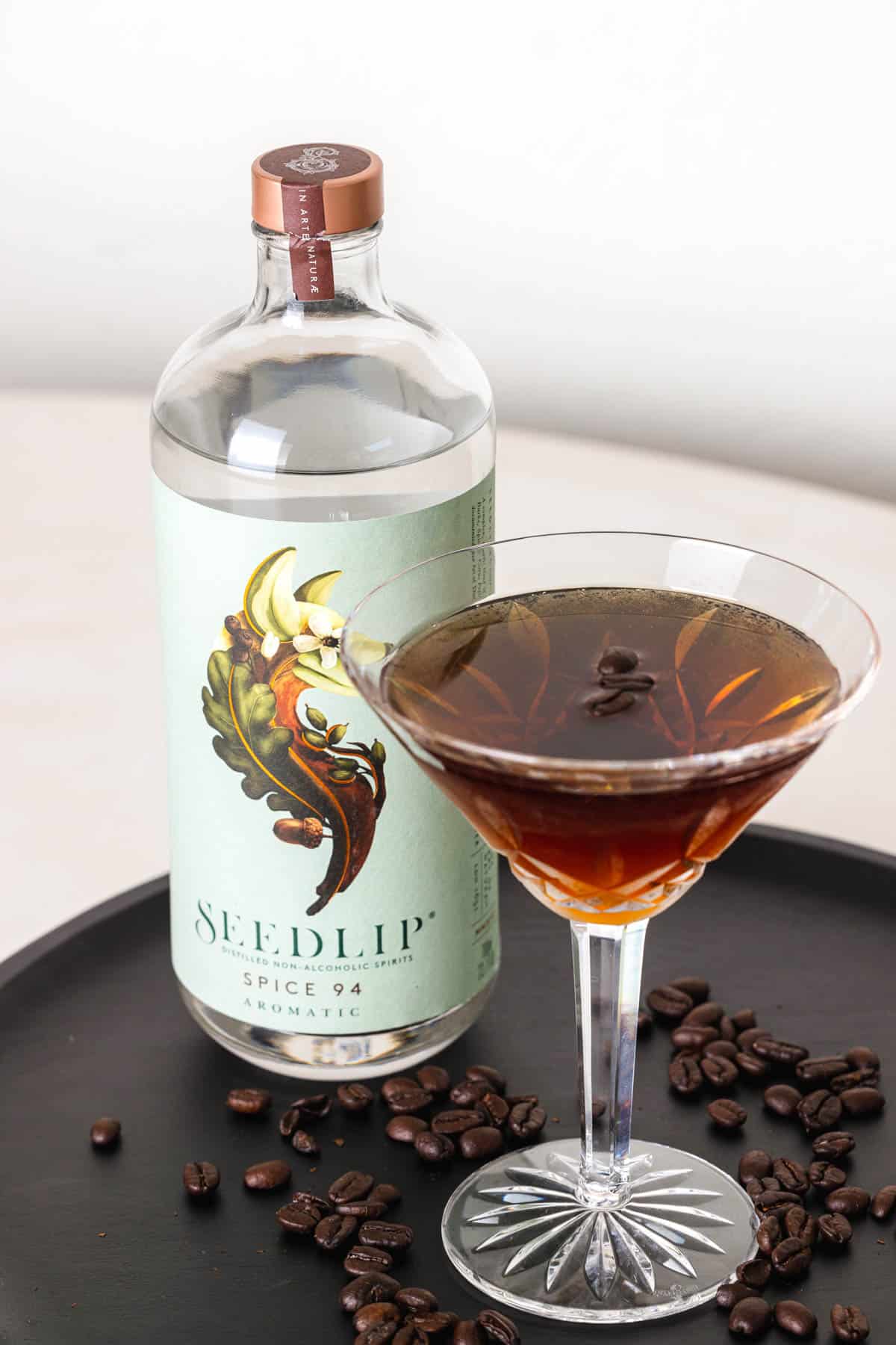 Virgin espresso martini mocktail on a tray next to a bottle of Seedlip 94.