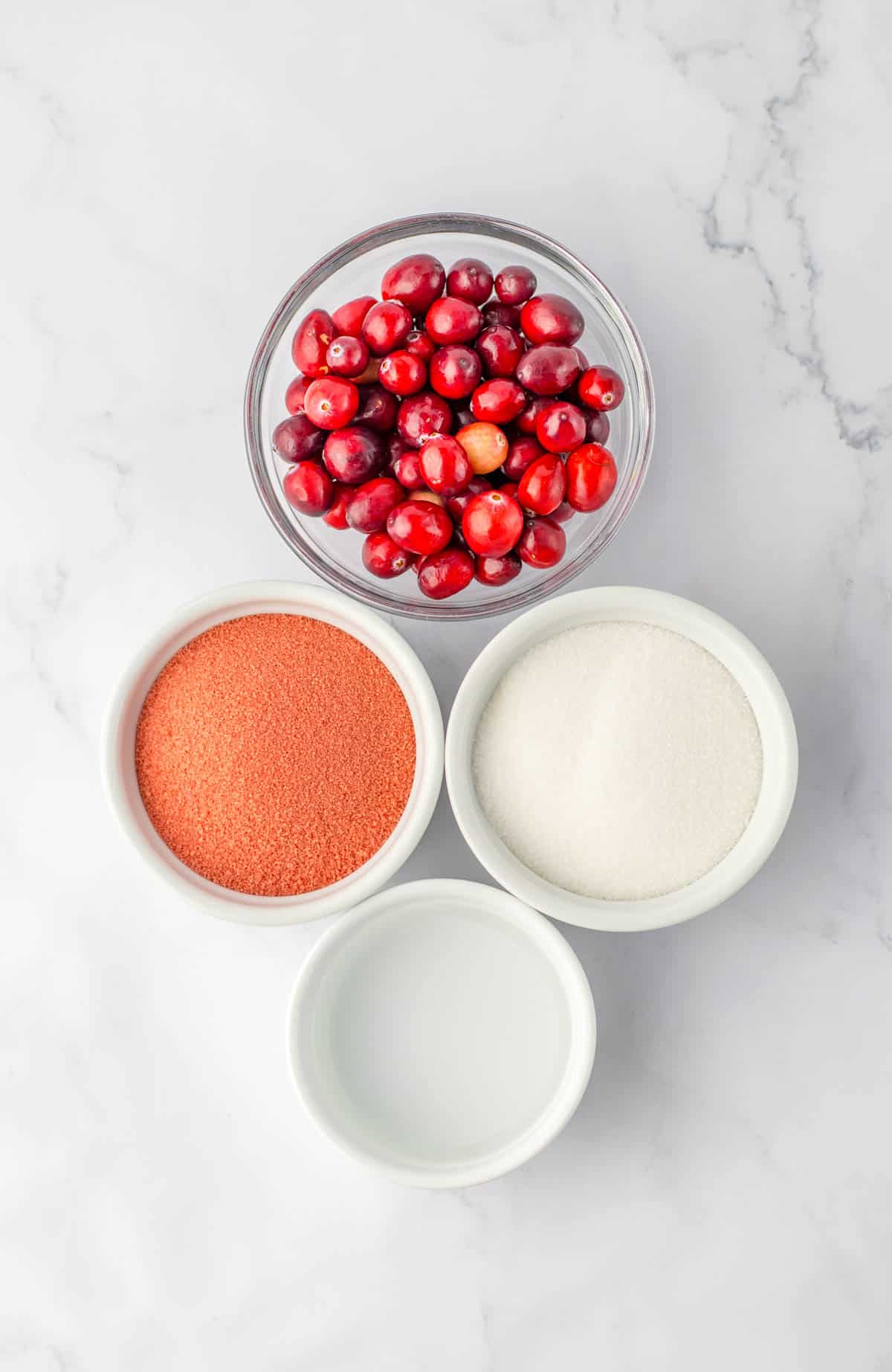Ingredients to make Cranberry Jello Shots with vodka on a table in white bowls.