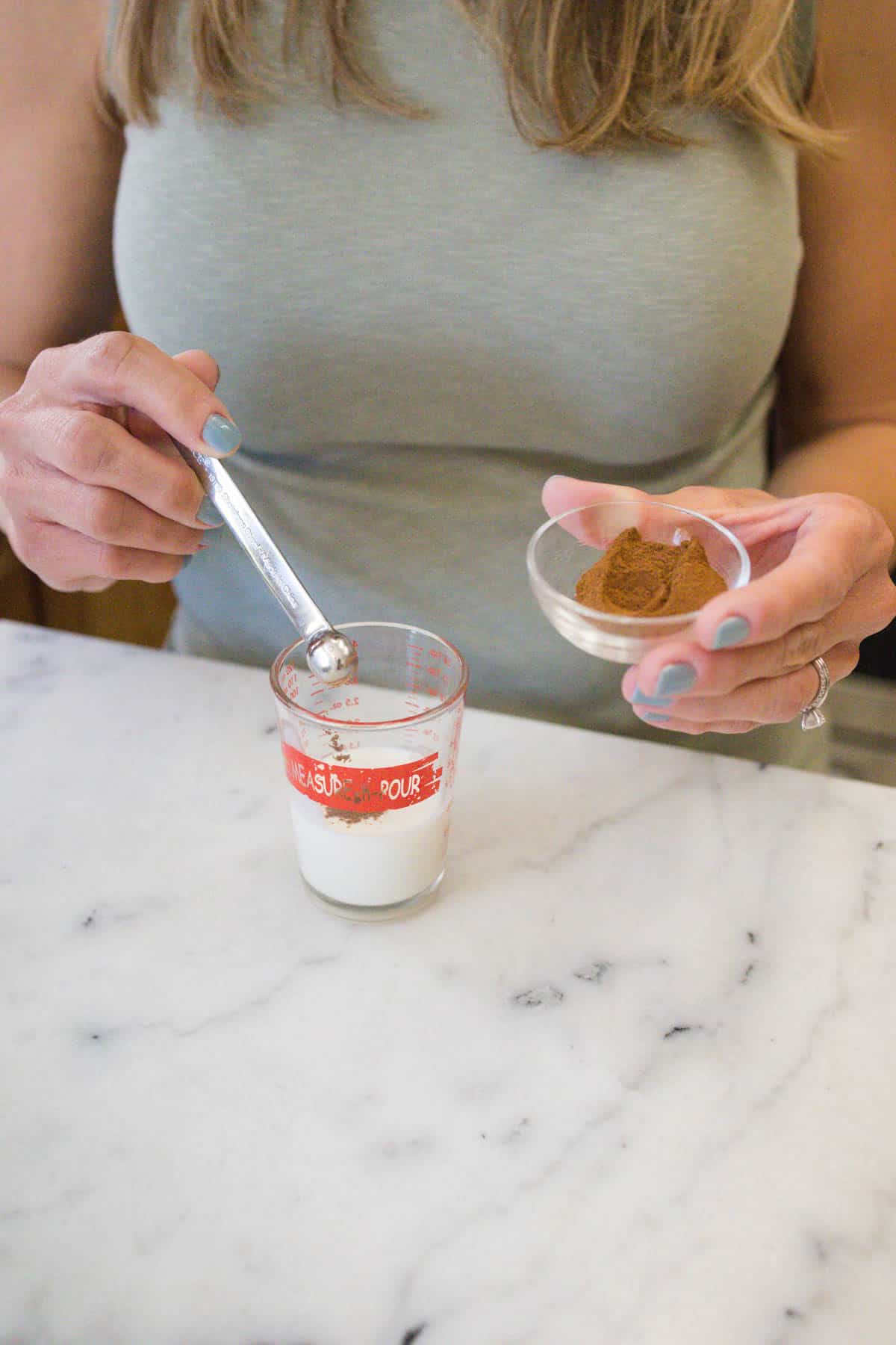 Woman spooning cinnamon into heavy cream.