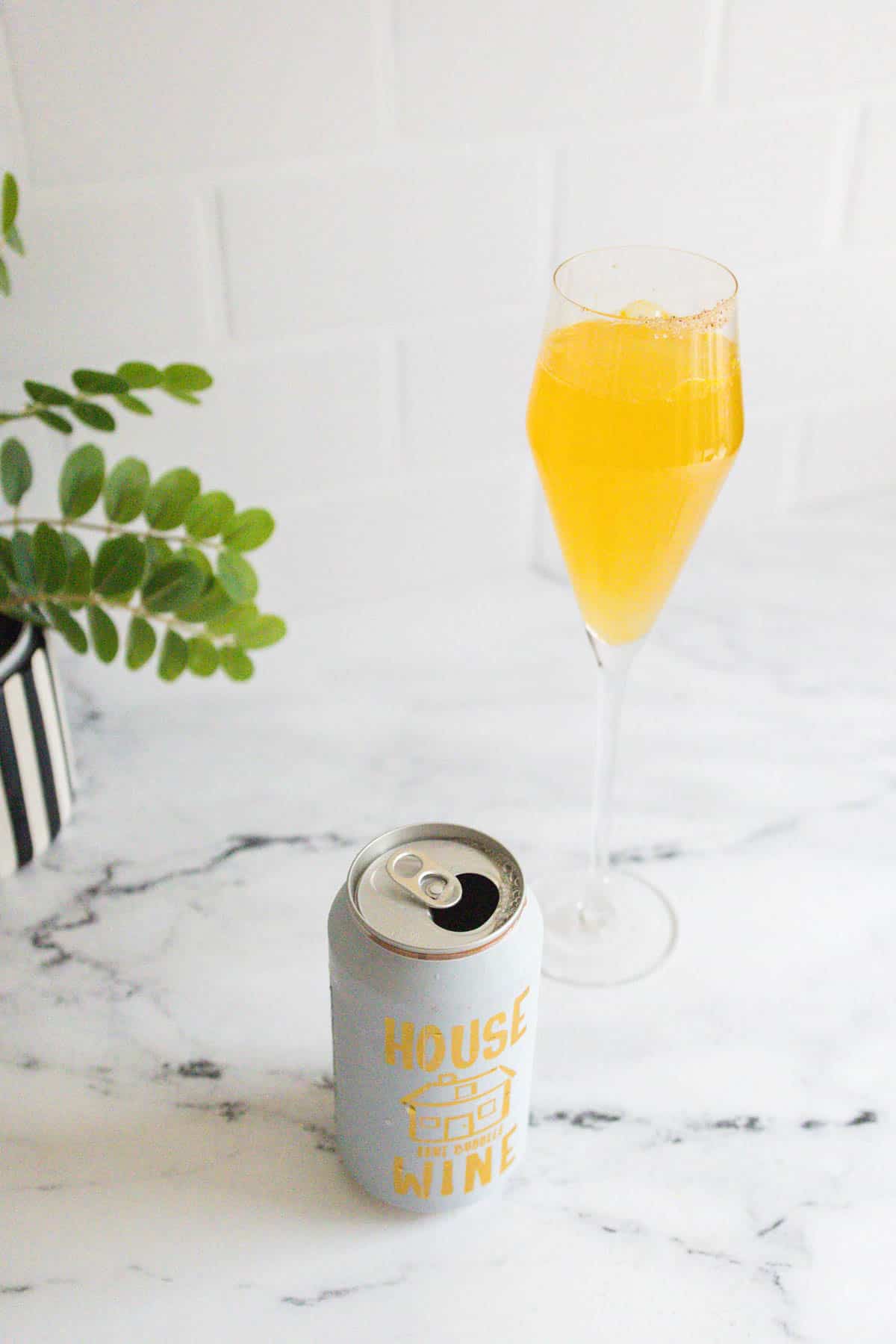 Mimosa next to an open can of sparkling wine.