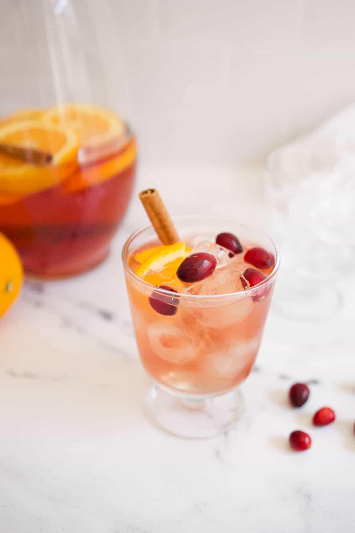 Fireball sangria served in a short wine glass with the pitcher in the background.