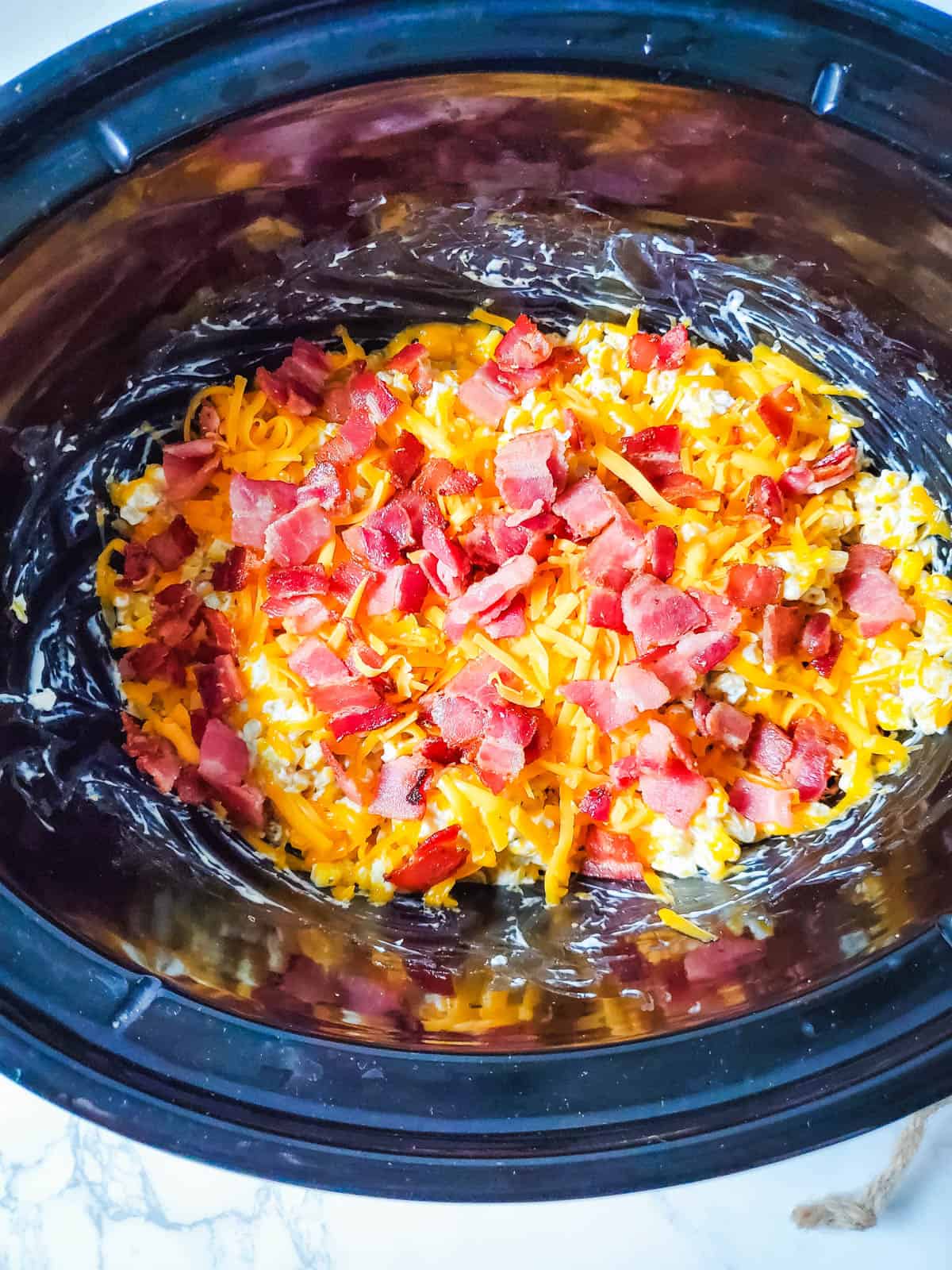 Bacon topped cheese and corn in a crockpot.