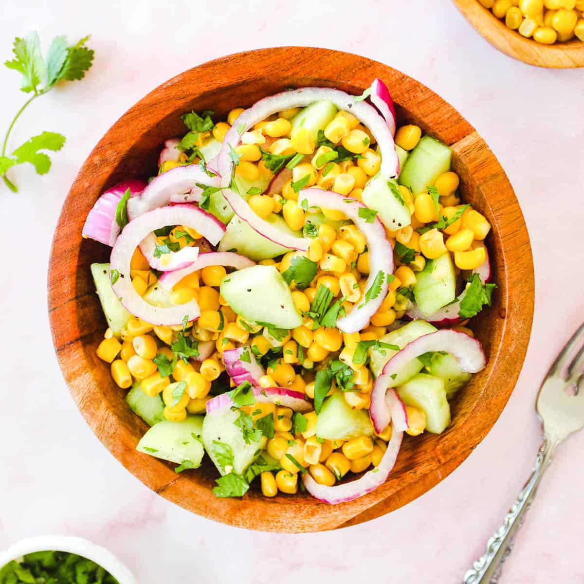 Overhead picture of corn and cucumber salad on a wooden bowl.