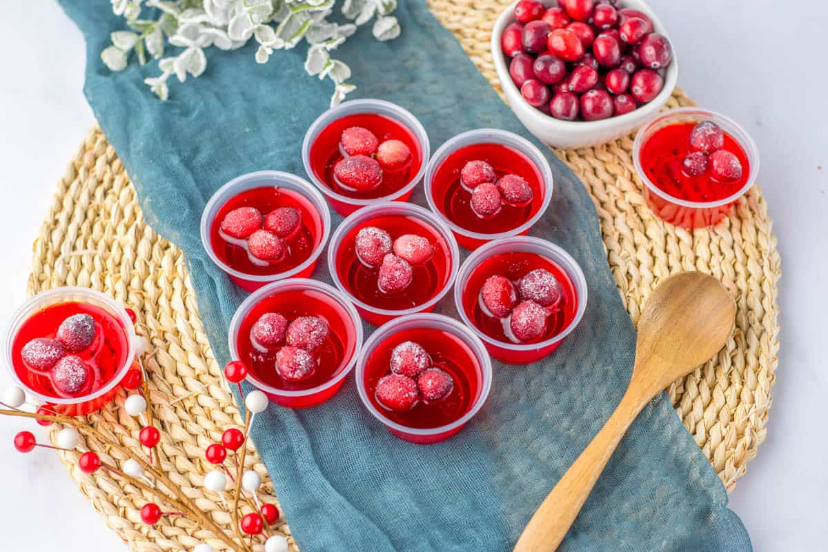Winter jello shots made with cranberry jello and topped with fresh cranberries on a table.