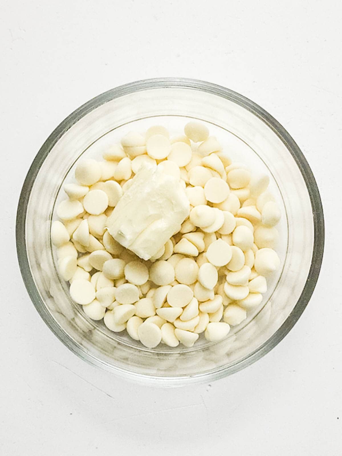 White chocolate chips and butter in a glass mixing bowl.