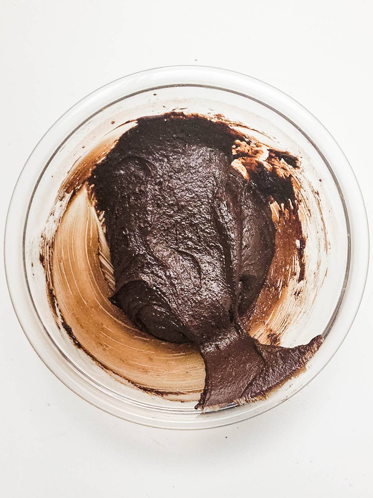 Dark chocolate cookie dough on a glass mixing bowl.