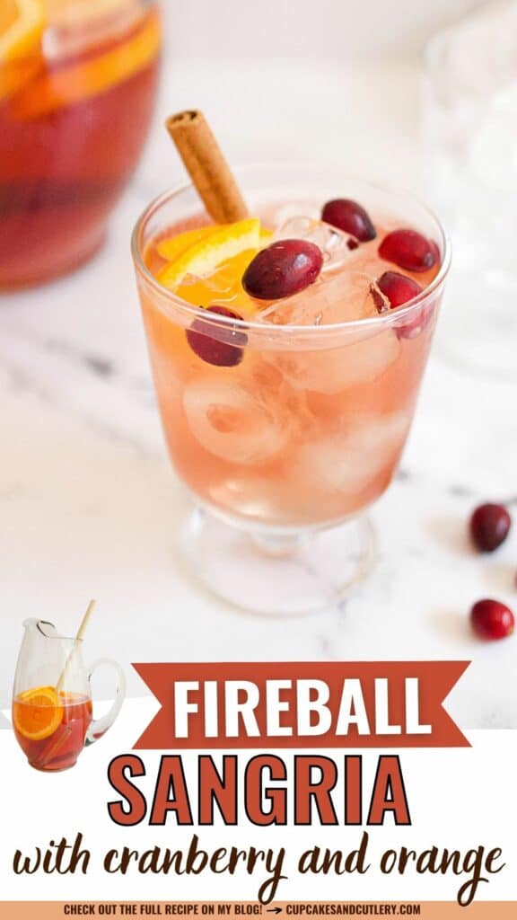 Close up of a short wine glass with Fireball sangria garnished with fresh cranberries, an orange slice and a cinnamon stick.