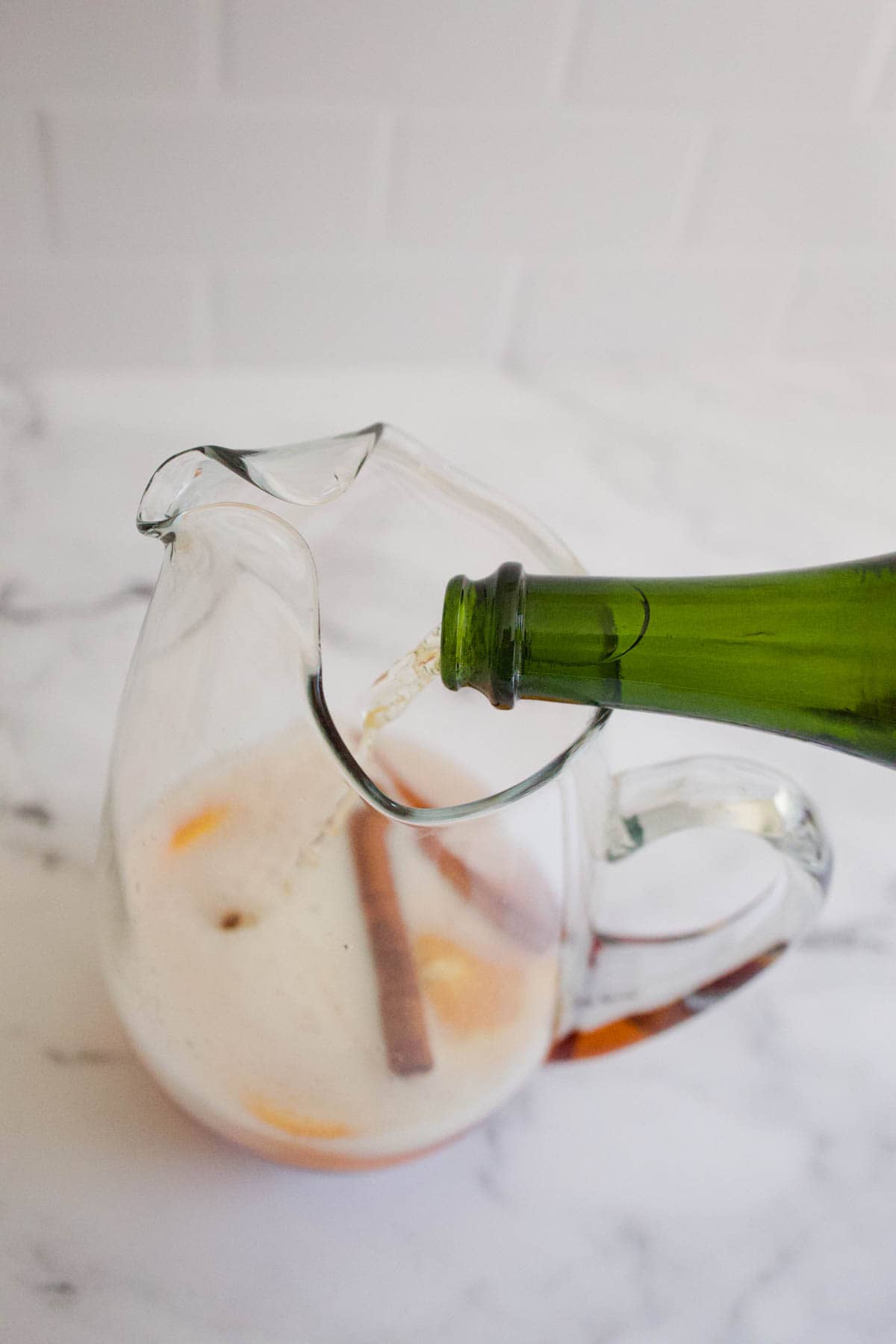 Sparkling wine being poured into a glass pitcher.