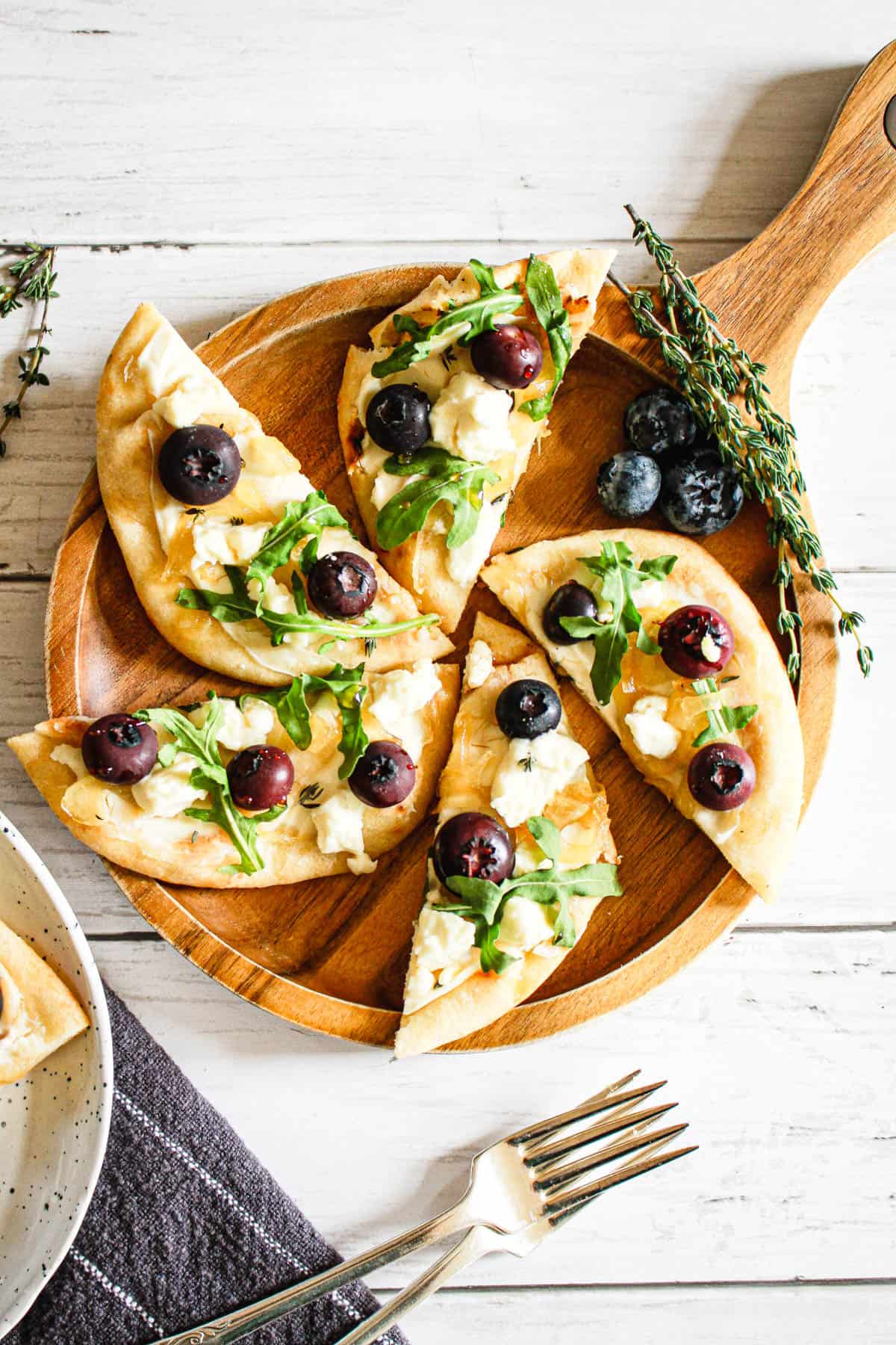 Sliced honey goat cheese flatbread on a wooden serving dish.