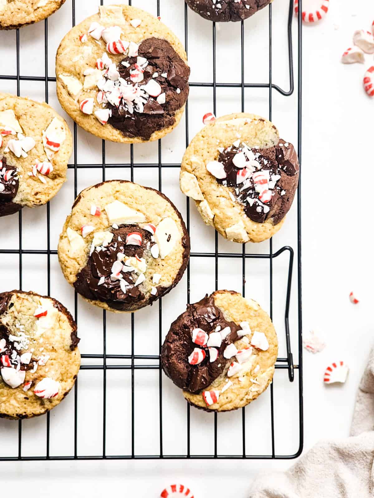 Overhead image of marbled Christmas cookies on a wire rack topped with peppermint candy pieces and shaved white chocolate.