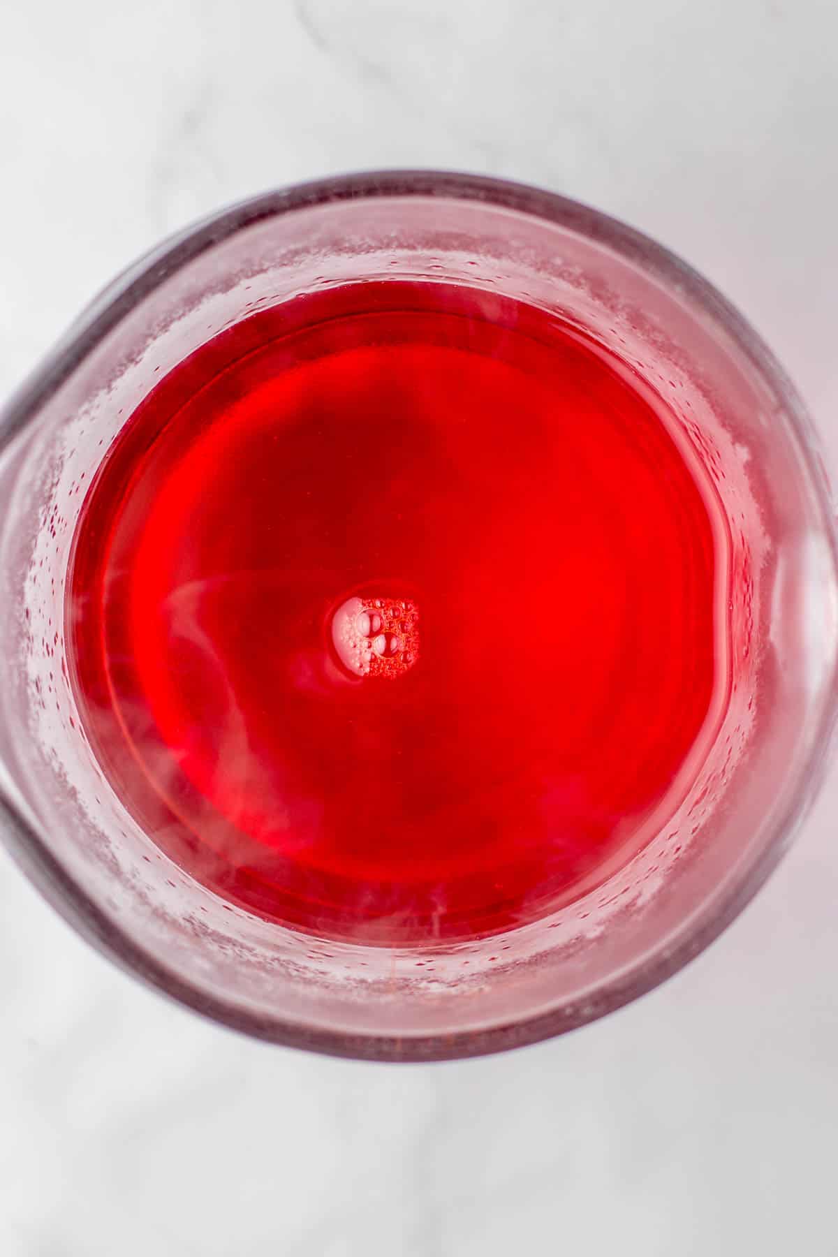 A bowl with cranberry jello that has been dissolved in water.