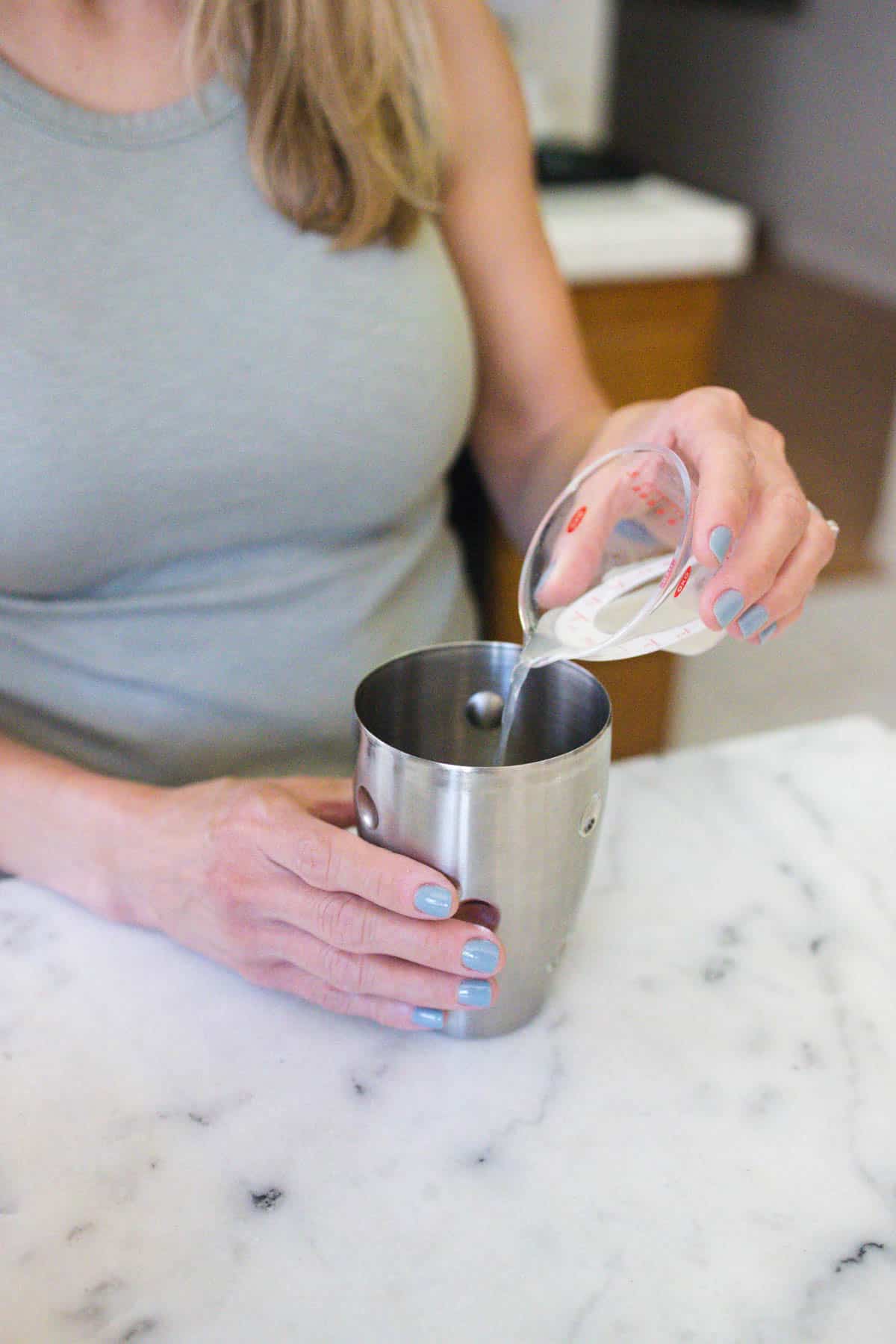 Woman pouring lime juice into a cocktail shaker.