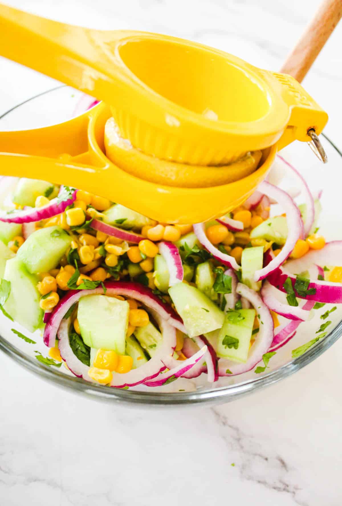 Squeezing fresh lemon juice onto corn and cucumber salad.