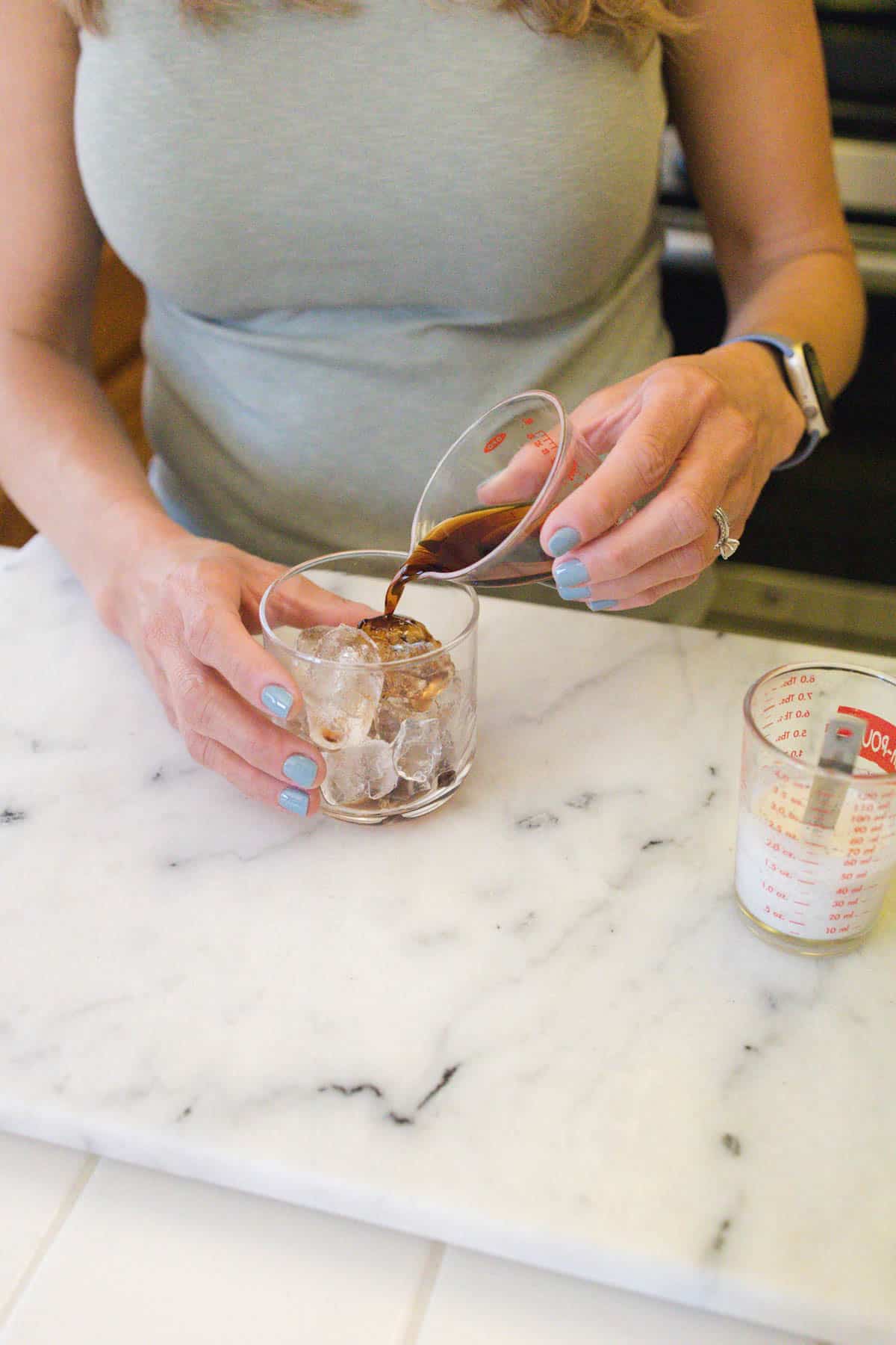 Woman pouring Kahlua over ice.