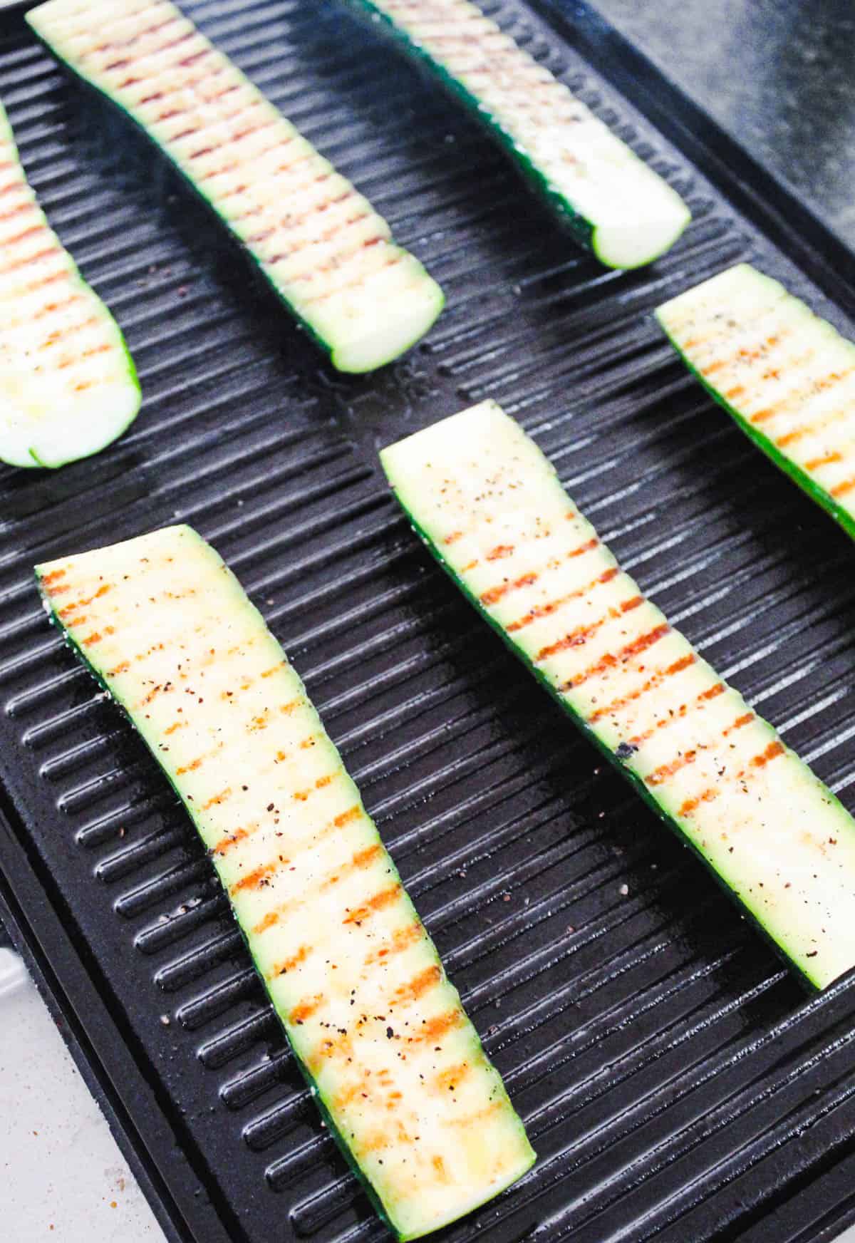 Zucchini halves on the grill with grill marks.