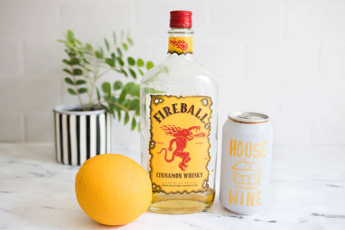 Ingredients to make a fireball mimosa on a white marble countertop.