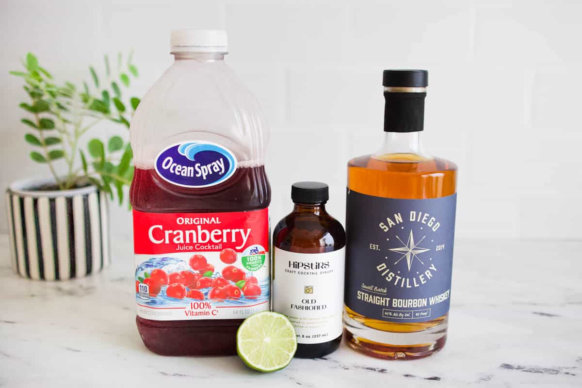 Ingredients to make a cranberry juice old fashioned on a table.