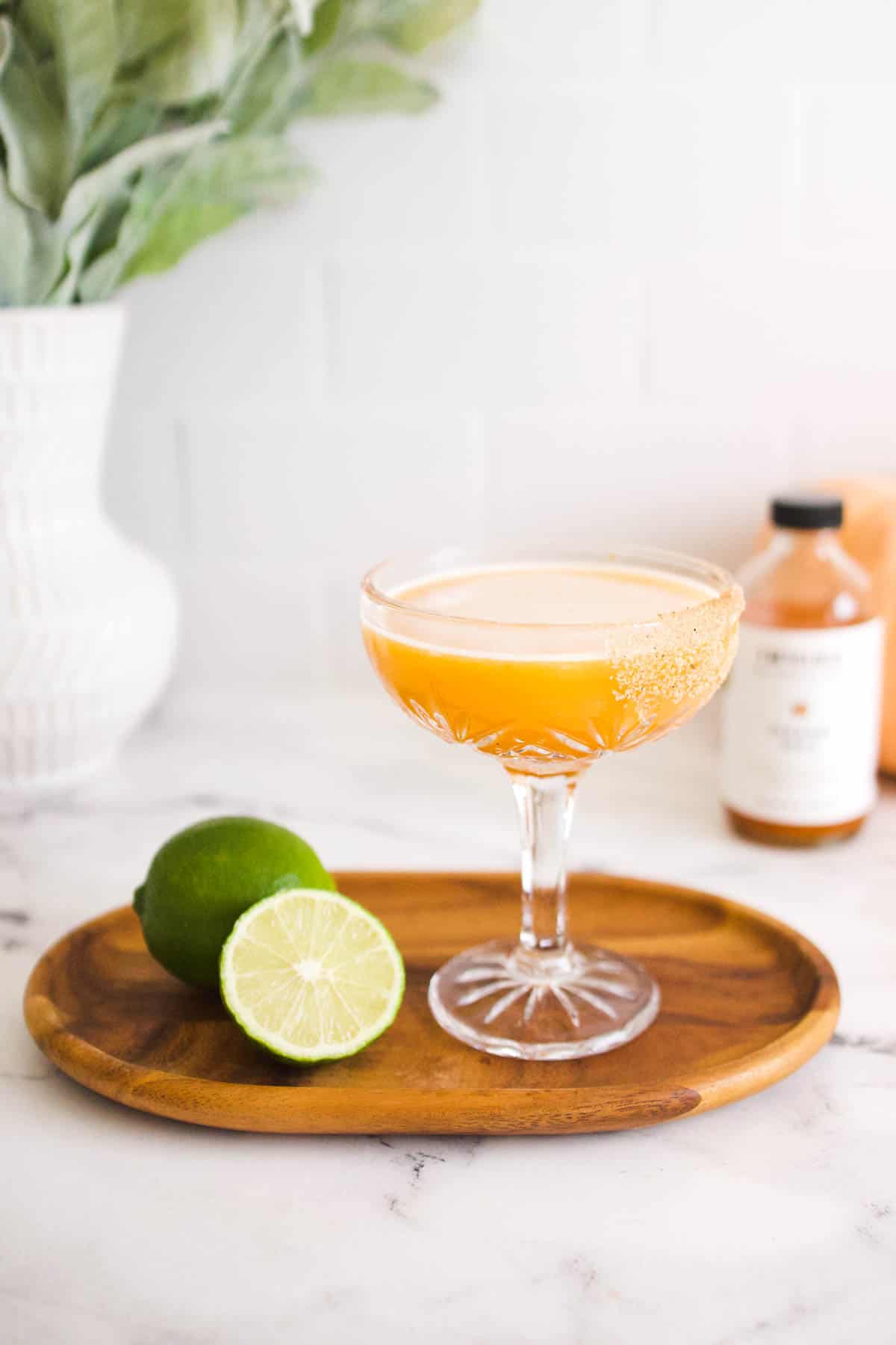 A coupe glass on a wooden tray holding a pumpkin daiquiri.