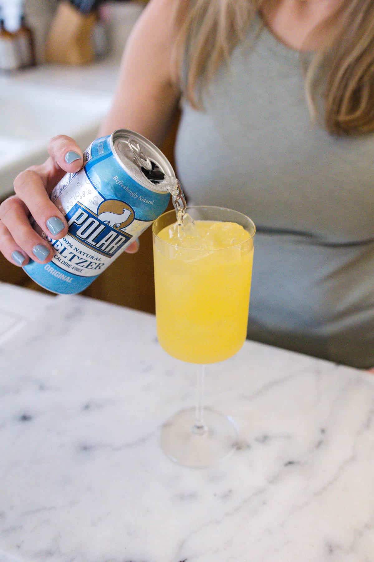 Tequila spritzer being topped up from a can of soda water.